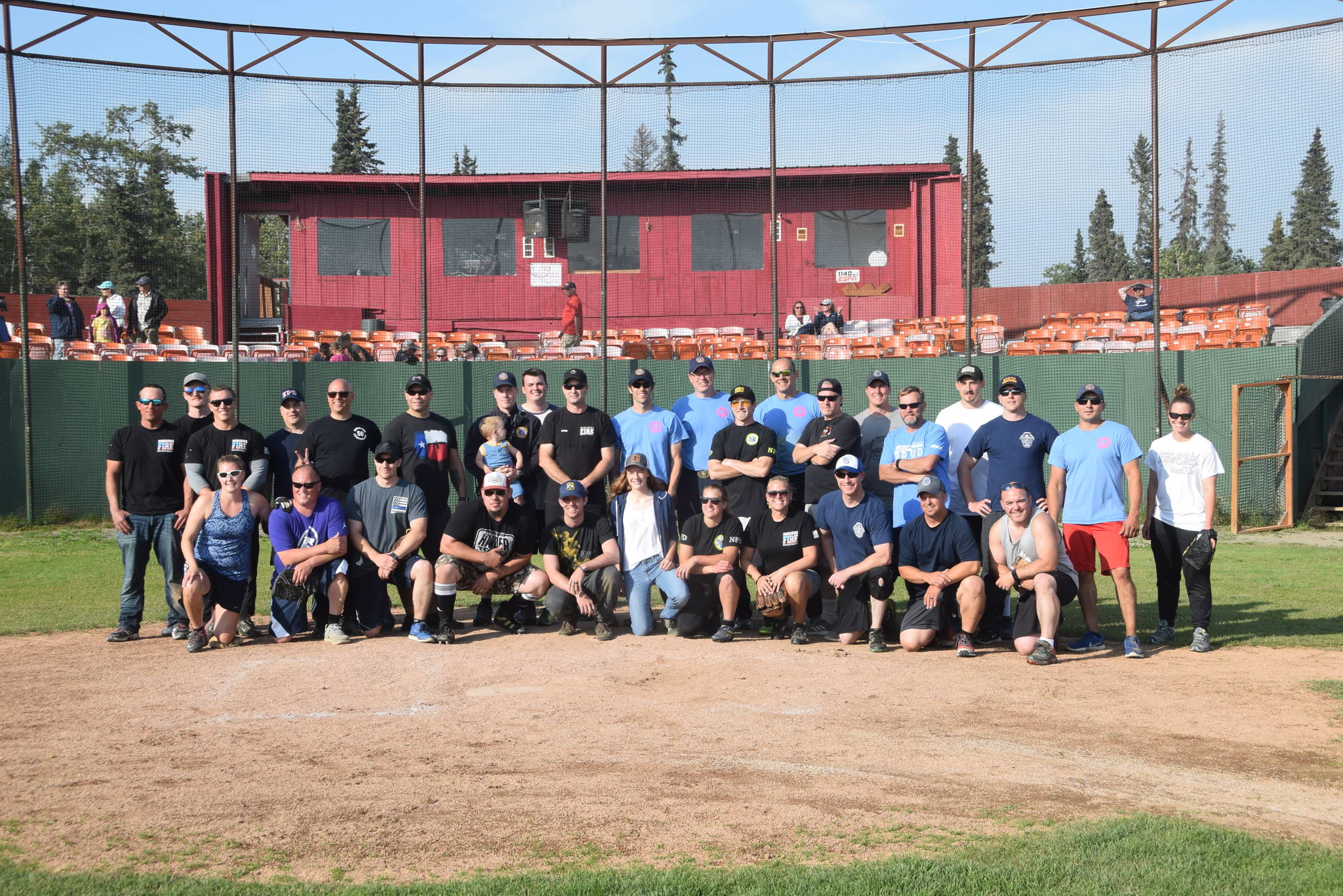 Local firefighters and law enforcement pose for a group photo after the third annual Guns and Hoses charity baseball game at Coral Seymour Memorial Park in Kenai, Alaska on July 19, 2019. The firefighters mounted an inspiring comeback in the last inning, but law enforcement won the game 6-5 and remain undefeated in the series. Bailey Epperheimer, front center, is the executive director of the Nikiski Children’s Fund and said that the game raised over $1800 for the fund, which is the most the nonprofit has raised at a single event. (Photo by Brian Mazurek/Peninsula Clarion)