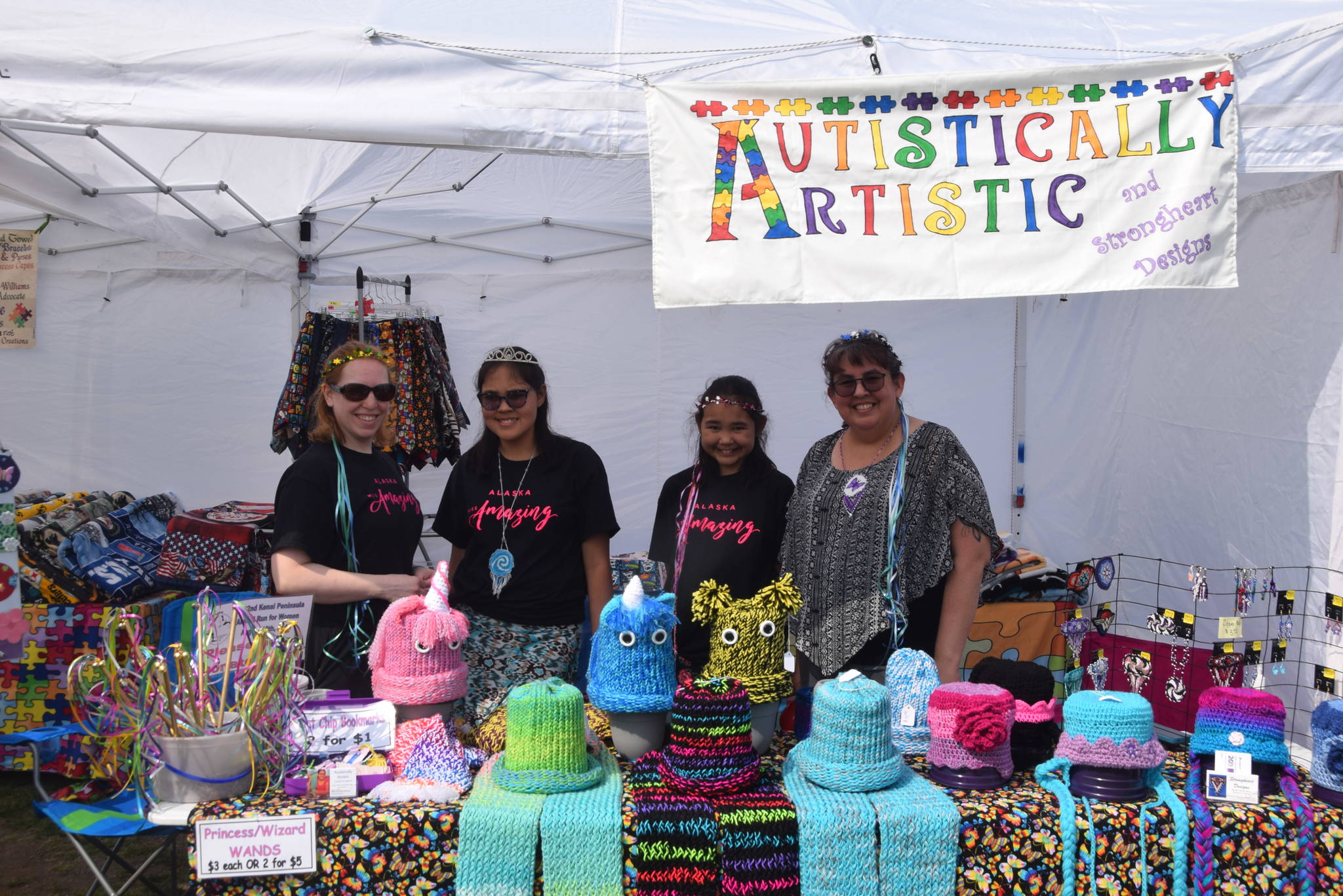 From left, Jennifer Pelka, Cece Strongheart, Glenna Strongheart and Ann Strongheart pose for a photo at their vendor booth during the 2019 Disability Pride Celebration in Soldotna Creek Park on July 20, 2019. Cece, who is autistic, knits hats and makes various crafts to sell such as bookmarks and stickers. (Photo by Brian Mazurek/Peninsula Clarion)