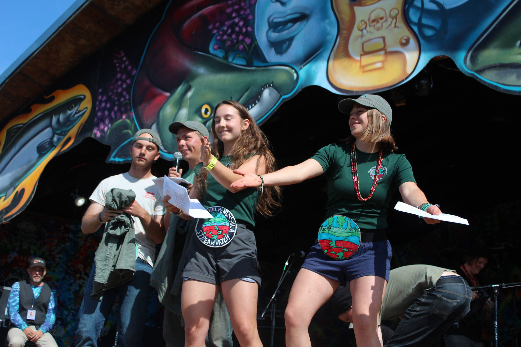 Members of the Kenai Watershed Forum sing an educational tune promoting the Stream Watch program during a break between bands on the Ocean Stage at Salmonfest on Saturday, Aug. 4, 2018 at the Kenai Peninsula Fairgrounds in Ninilchik, Alaska. (Photo by Megan Pacer/Homer News)