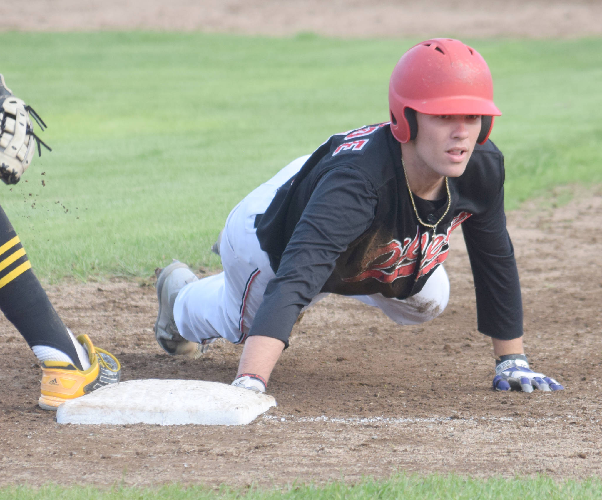 Peninsula Oilers’ Bobby Goodloe dives back safely to first base against the Anchorage Bucs on Wednesday, July 24, 2019, at Coral Seymour Memorial Park in Kenai, Alaska. (Photo by Jeff Helminiak/Peninsula Clarion)