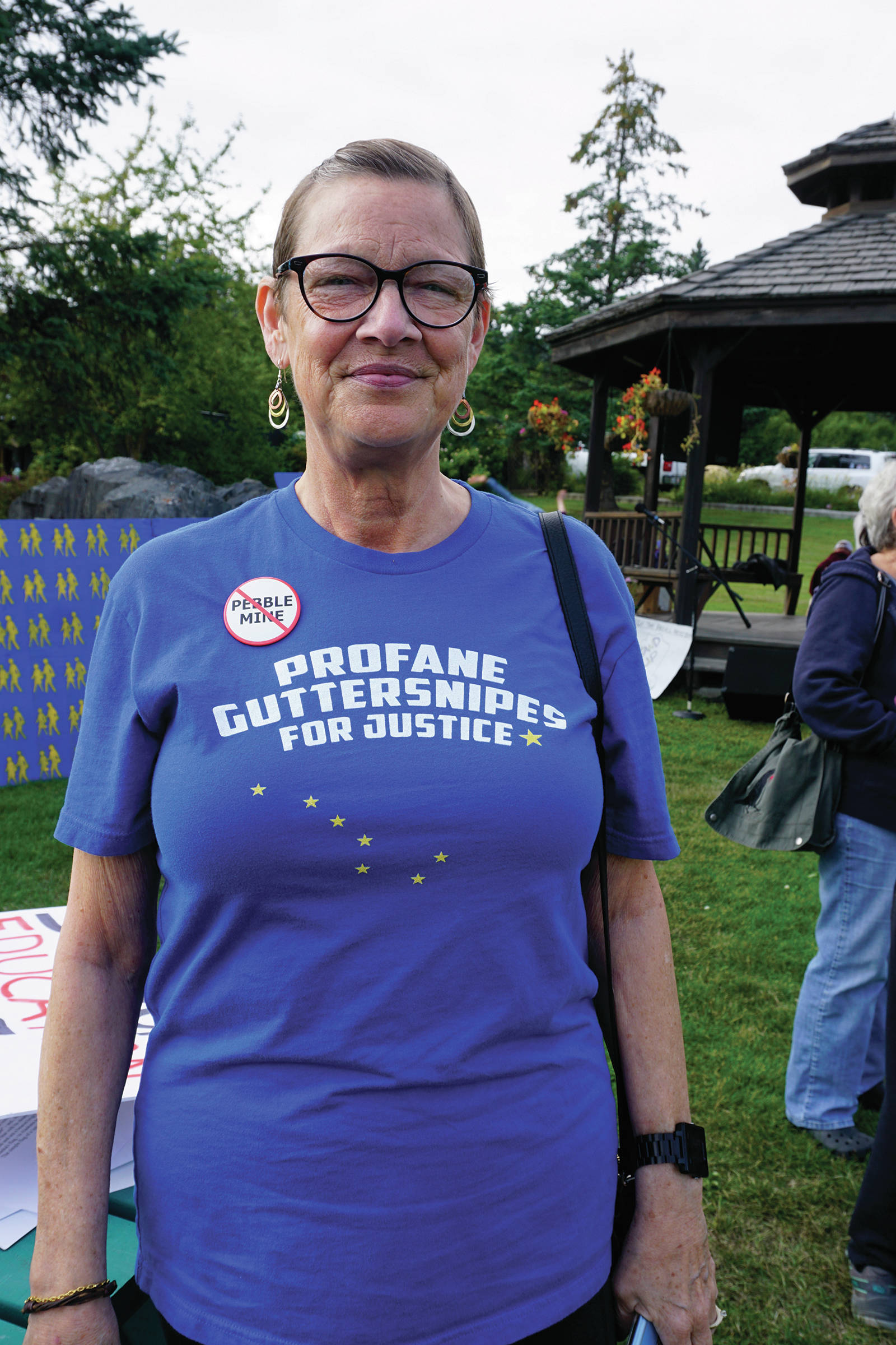 Michele Vasquez wears a “profane guttersnipes for justice” T-shirt at a Recall Dunleavy rally held on Aug. 1, 2019, at WKFL Park in Homer, Alaska. The slogan comes from a Republican Party reference to people who protested a Wasilla Middle School during the special session held earlier in July. Vasquez and her husband, Larry Simmons, visited Homer from Soldotna and stopped by the rally to sign recall petitions. (Photo by Michael Armstrong)