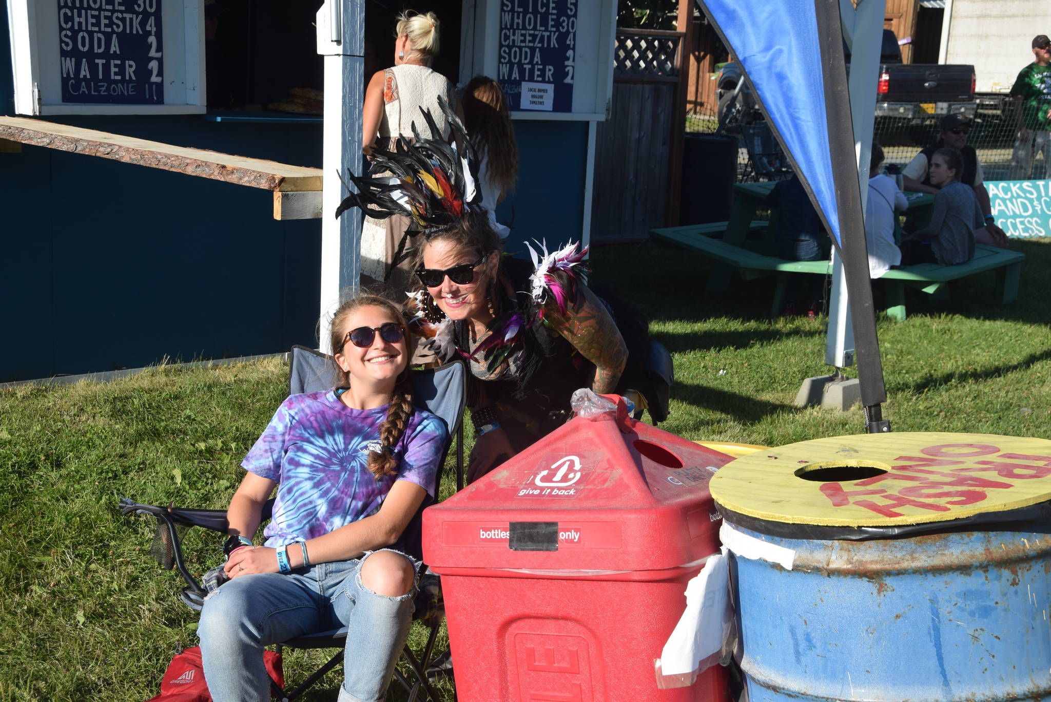 Rosie Skovron, left, and a Salmonfest attendee smile for the camera at one of the waste disposal stations during Salmonfest 2019 in Ninilchik, Alaska on August 2, 2019. Skovron is a volunteer for the Zero Waste project and an intern at Cook Inletkeeper. (Photo by Brian Mazurek/Peninsula Clarion)