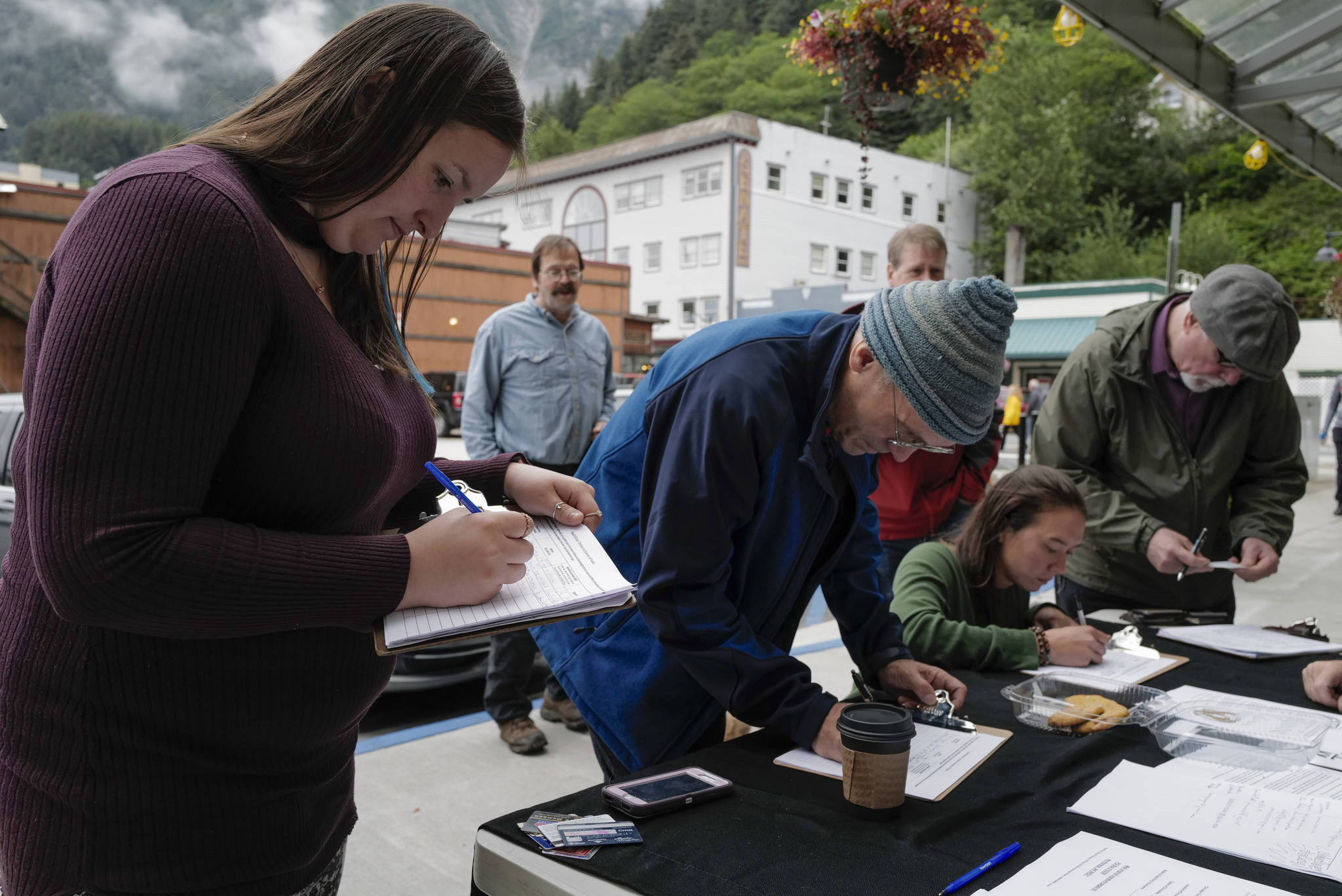 Michael Penn | Juneau Empire                                Monika Kunat (left) signs an application petition to recall Gov. Mike Dunleavy on Thursday with others at the Planet Alaska Gallery in Juneau.