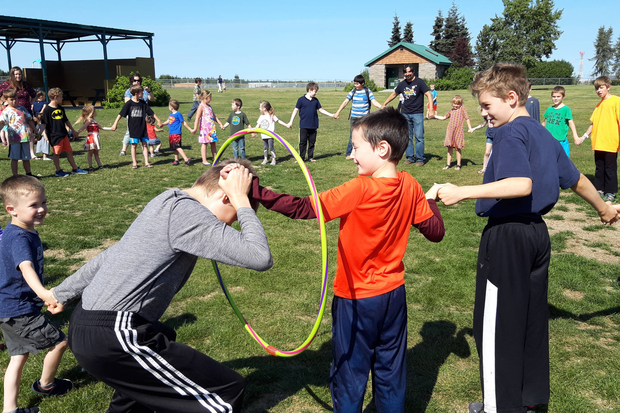 Kids attempt to travel through a “space portal”, also known as a hula hoop, during the last day of the Kenai Community Library’s summer reading program at the Kenai Park Strip on August 8, 2019. (Photo by Brian Mazurek/Peninsula Clarion)