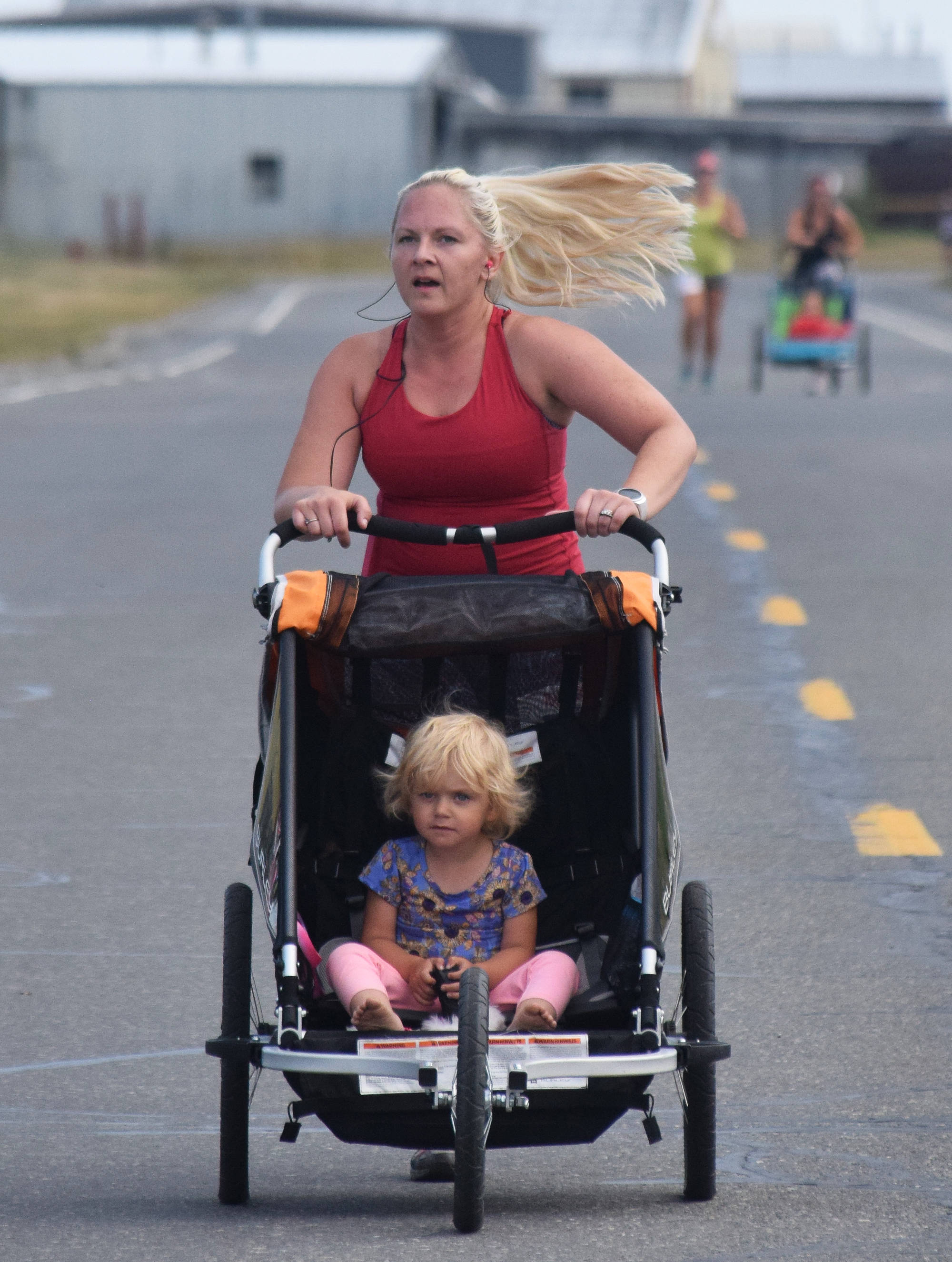 A 5K runner pushing a stroller approaches the finish line Saturday, Aug. 10, 2019, at the 32nd annual Run for Women in Kenai, Alaska. (Photo by Joey Klecka/Peninsula Clarion)