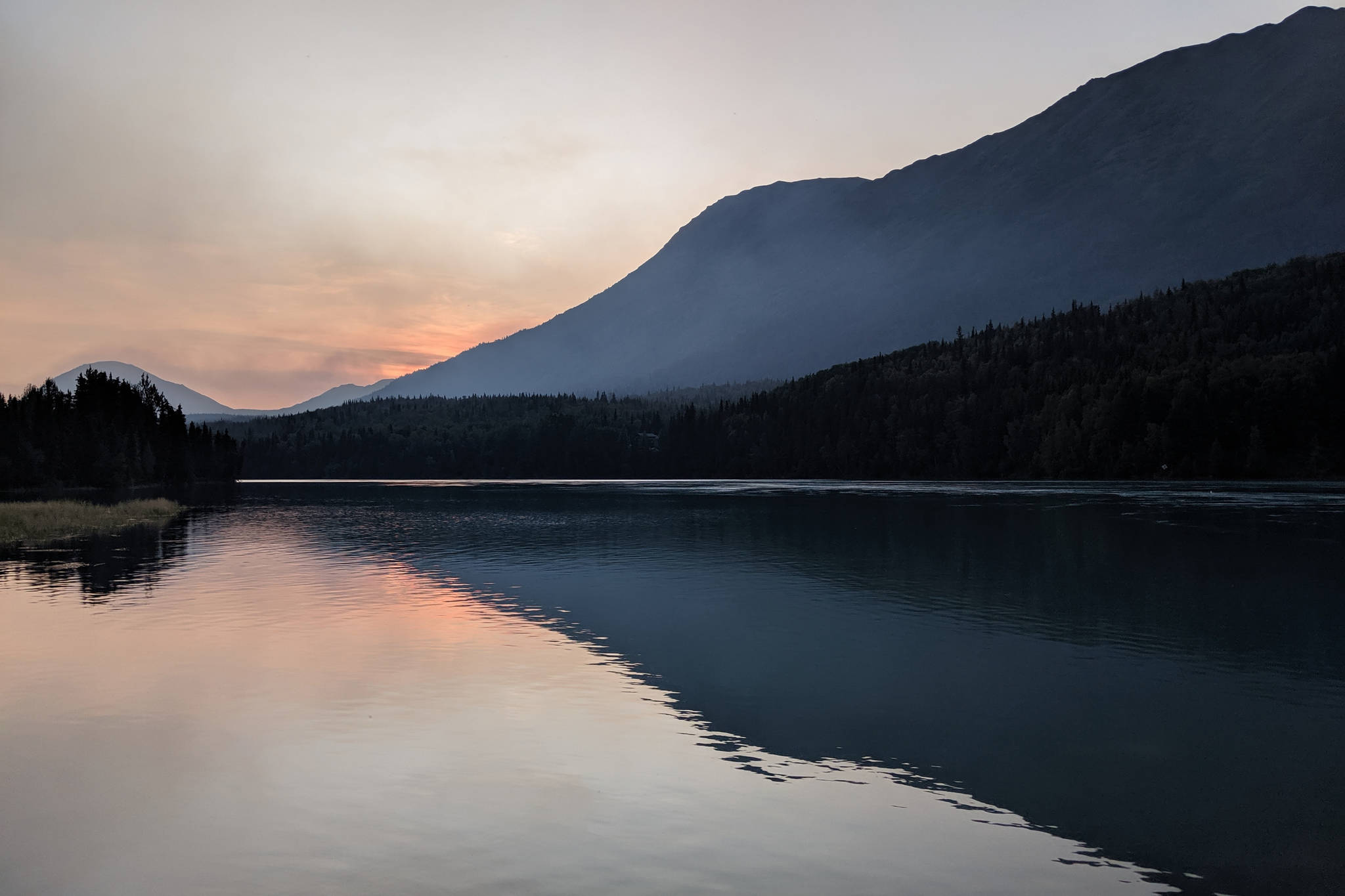 Smoke can be seen on the horizon at sunset on Sunday, Aug. 11, 2019, from Cooper Landing, Alaska. High temperatures and dry conditions have caused the 102,548-acre Swan Lake Fire burning in the Kenai National Wildlife Refuge east of Sterling and north of the Sterling Highway to flare up. (Photo by Erin Thompson/Peninsula Clarion)