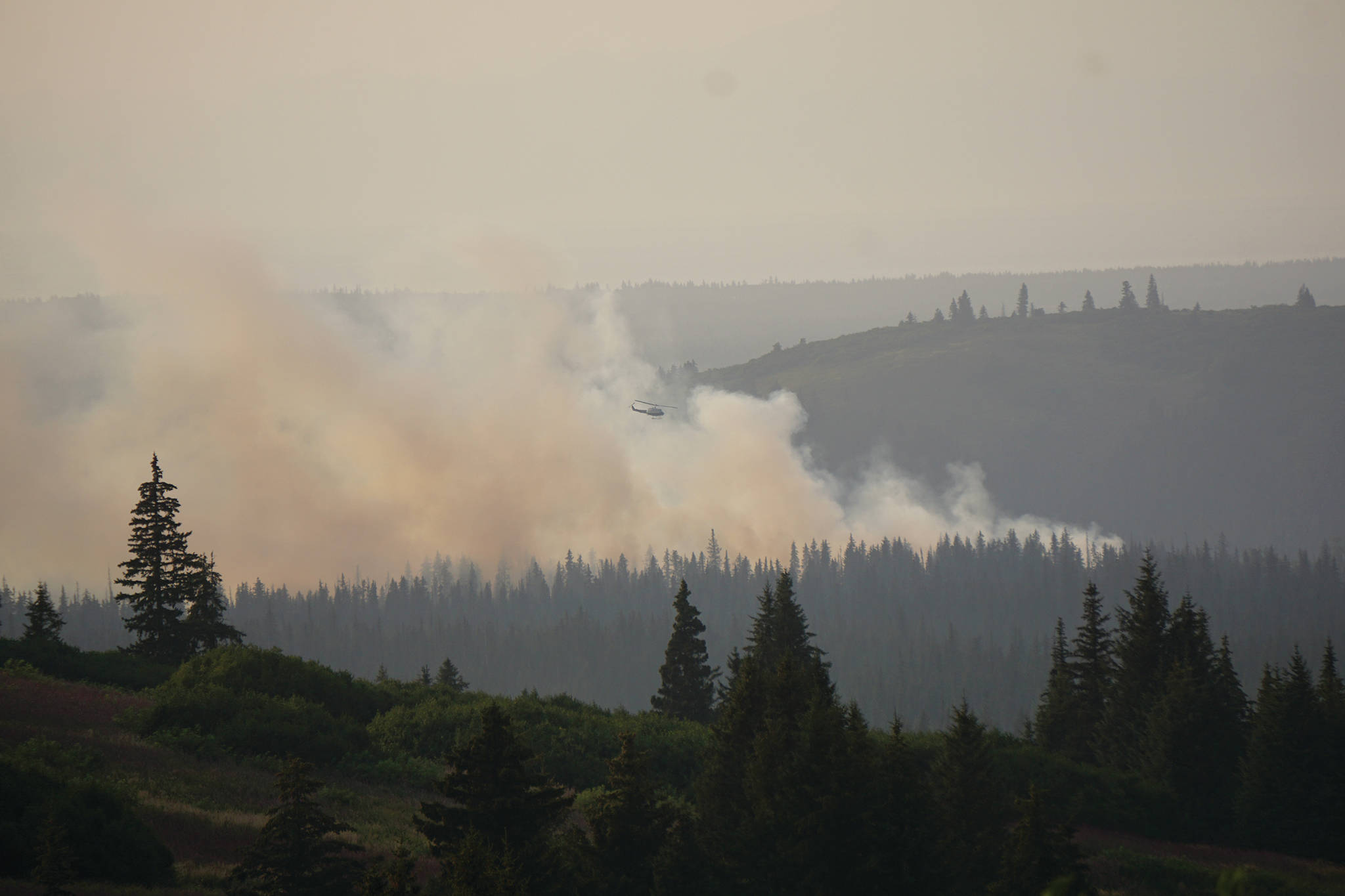 Michael Armstrong / Homer News                                 A helicopter flies over the North Fork fire as it burns near the south end of the North Fork Road on Sunday evening, Aug. 18, 2019, near Homer, Alaska, as seen from Diamond Ridge Road.