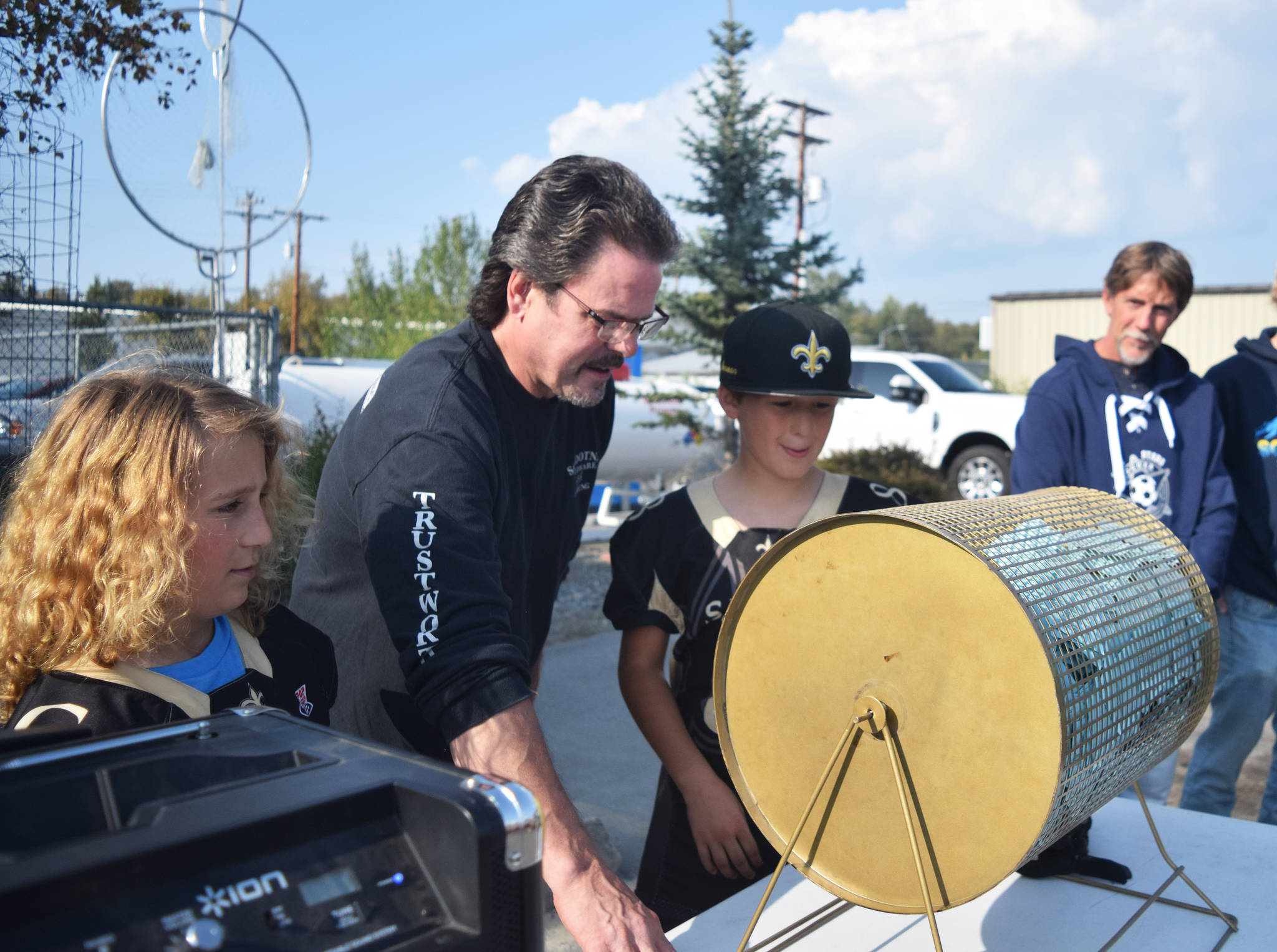 Trustworthy Hardware co-owner Brian Miller (middle) joins Kenai Peninsula Saints Pop Warner players Clayton McDonald (left) and Jameson Curren in picking a ticket in the Soldotna Trustworthy Youth Raffle event Friday in Soldotna.                                 Joey Klecka                                Peninsula Clarion