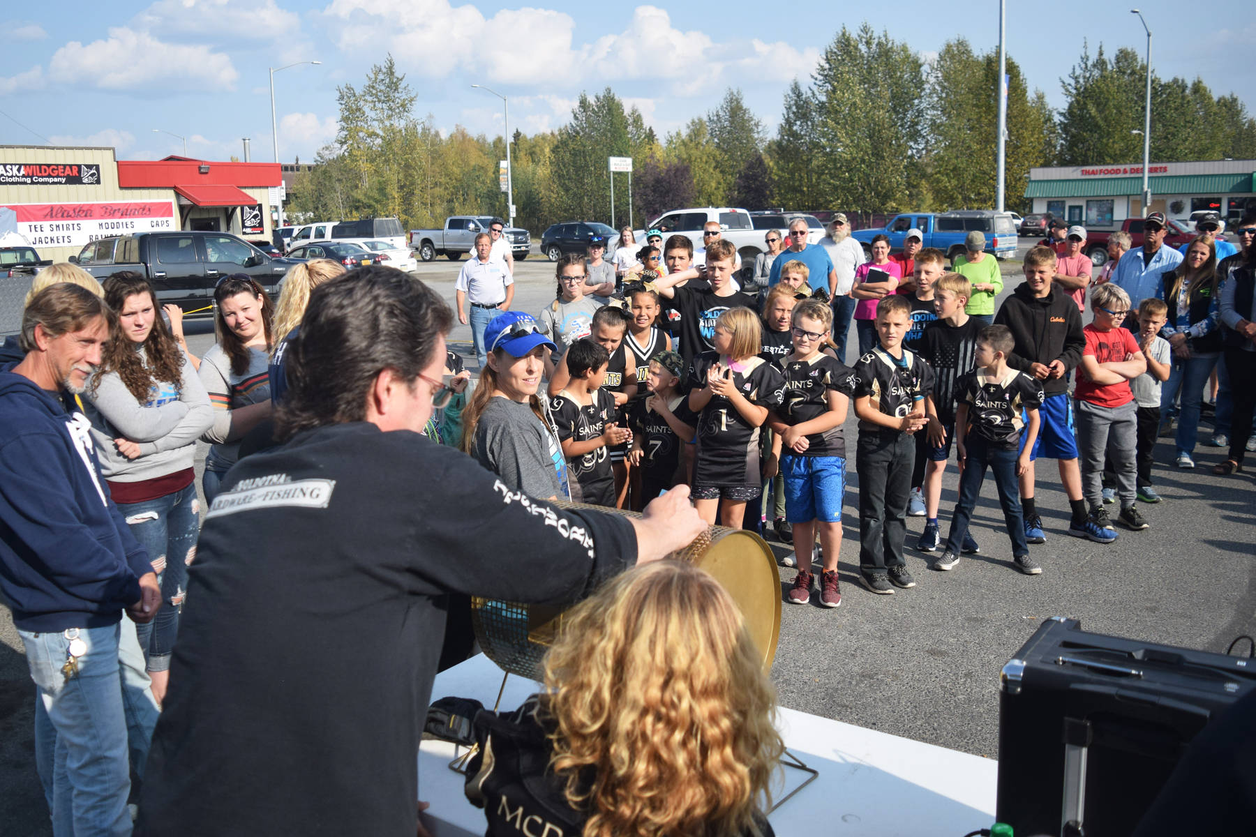 A group of players from the Kenai Peninsula Saints Pop Warner program gather around the ticket drawing at the Soldotna Trustworthy Youth Raffle event Friday, Aug. 23, 2019, in Soldotna, Alaska. (Photo by Joey Klecka/Peninsula Clarion)