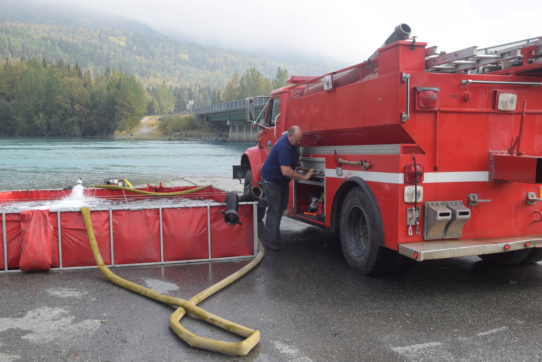 A firefighter from Cooper Landing Emergency Services refills a water tanker at the banks of the Kenai River in Cooper Landing, Alaska on Aug. 30, 2019. (Photo by Brian Mazurek/Peninsula Clarion)