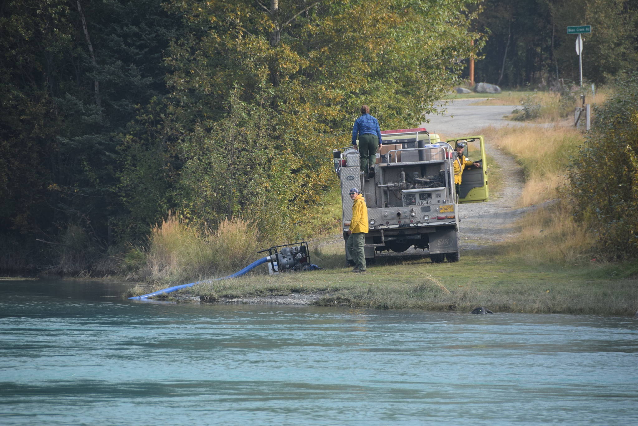 Firefighters stationed in Cooper Landing, Alaska refill a water tanker on the banks of the Kenai River on Aug. 30, 2019. (Photo by Brian Mazurek/Peninsula Clarion)