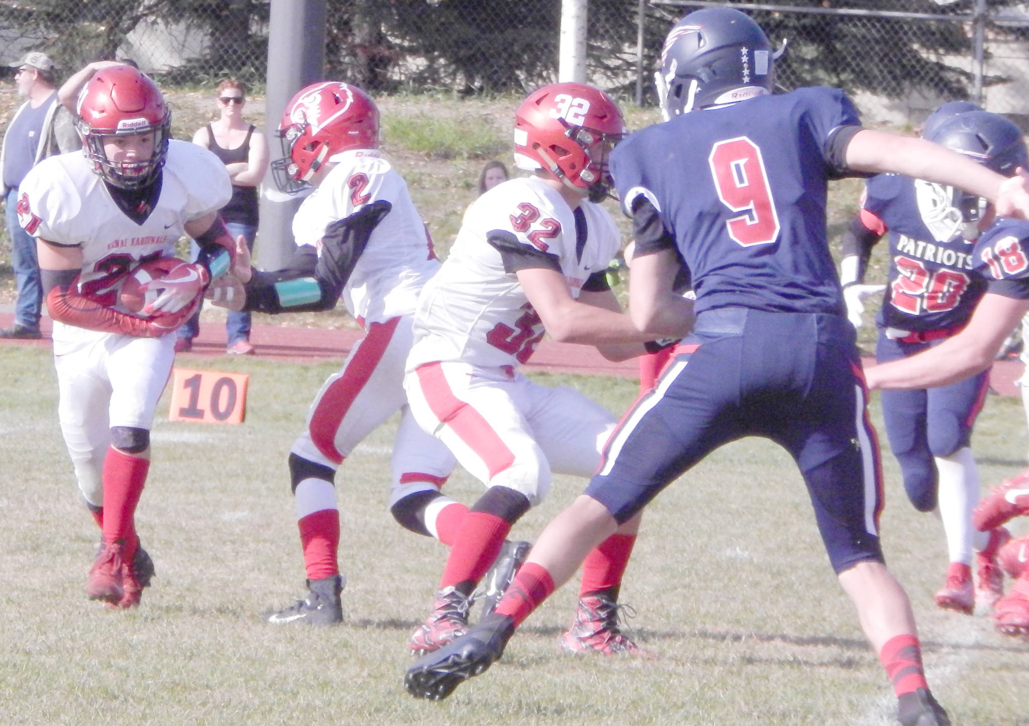 Kenai’s Zach Burnett takes a handoff from Kardinals quarterback Bridger Beck as Tucker Vann (32) gets in position and North Pole’s Alexander Melson (9) moves in during the fourth quarter of Saturday’s Division II nonconference game at North Pole High School. (Photo by Danny Martin/Fairbanks Daily News-Miner)