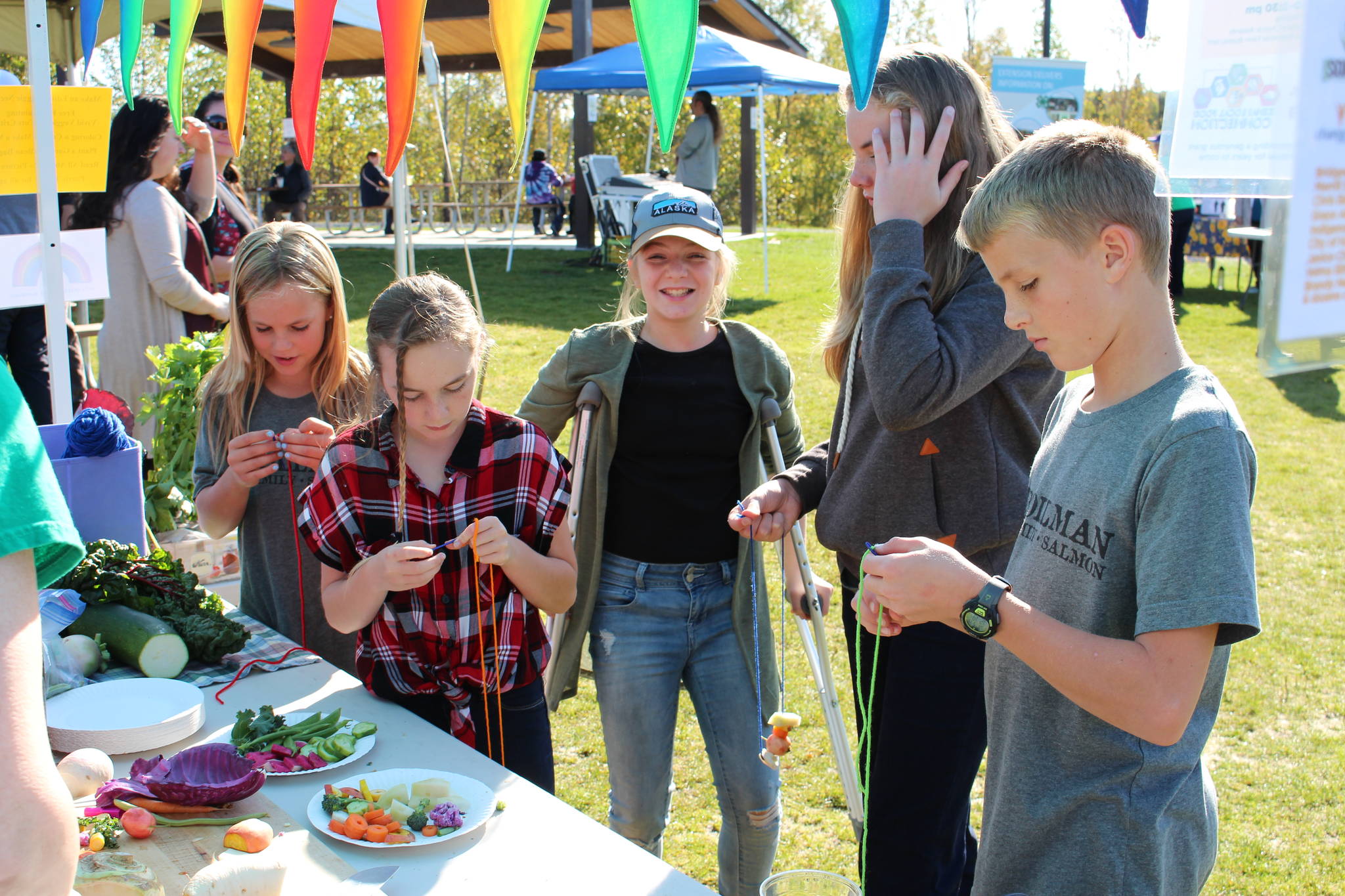 Kids make necklaces out of fresh vegetables at the Harvest Moon Local Food Festival at Soldotna Creek Park on Sept. 14, 2019. (Photo by Brian Mazurek/Peninsula Clarion)