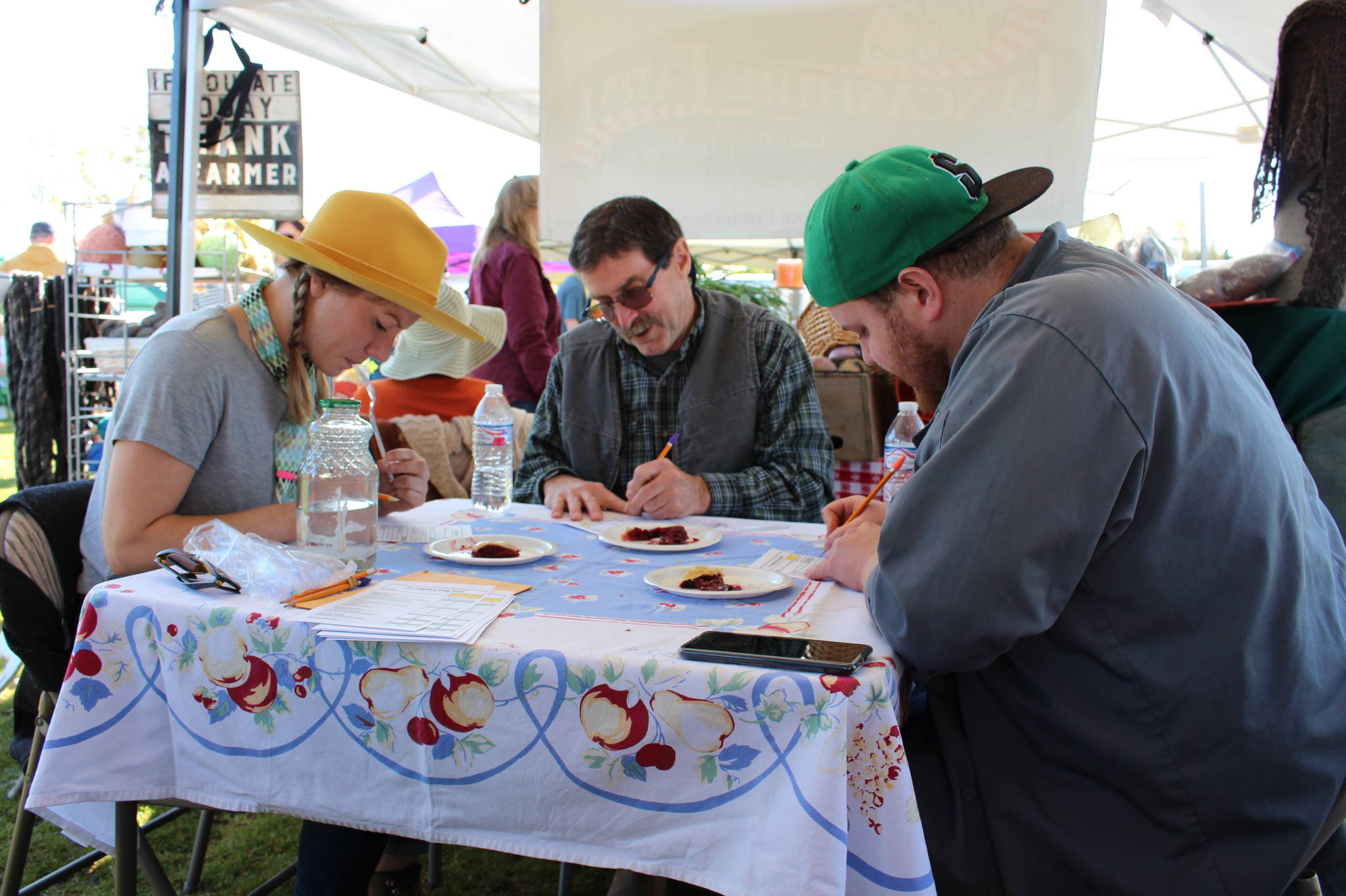 From left, pie contest judges Kelsey Shields, Larry Marsh and Joe Spady deliberate on the best pies at the Harvest Moon Local Food Festival at Soldotna Creek Park on Sept. 14, 2019. (Photo by Brian Mazurek/Peninsula Clarion)