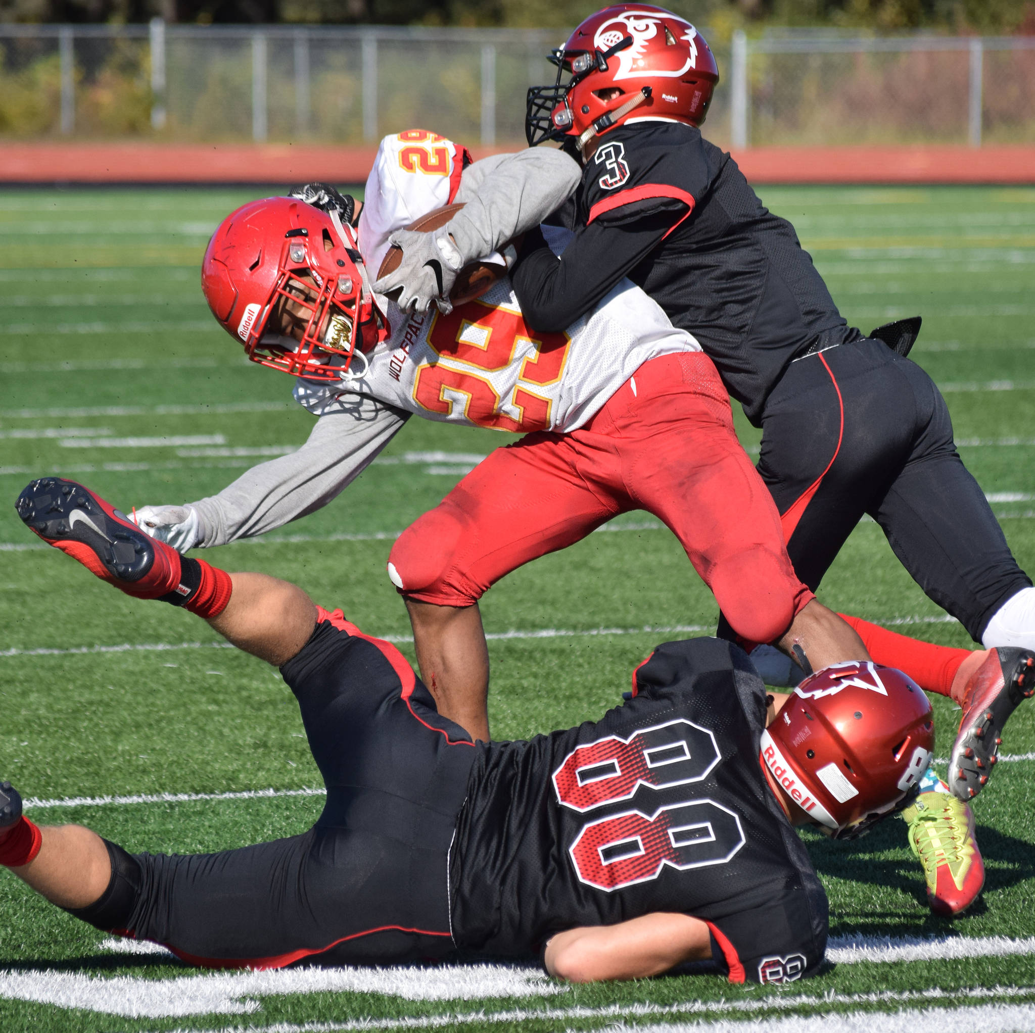 West Valley running back Justin Cummings is tackled by Kenai Central’s Jordan Smith (top) and Braedon Pitsch, Saturday, Sept. 14, 2019, at Ed Hollier Field in Kenai, Alaska. (Photo by Joey Klecka/Peninsula Clarion)