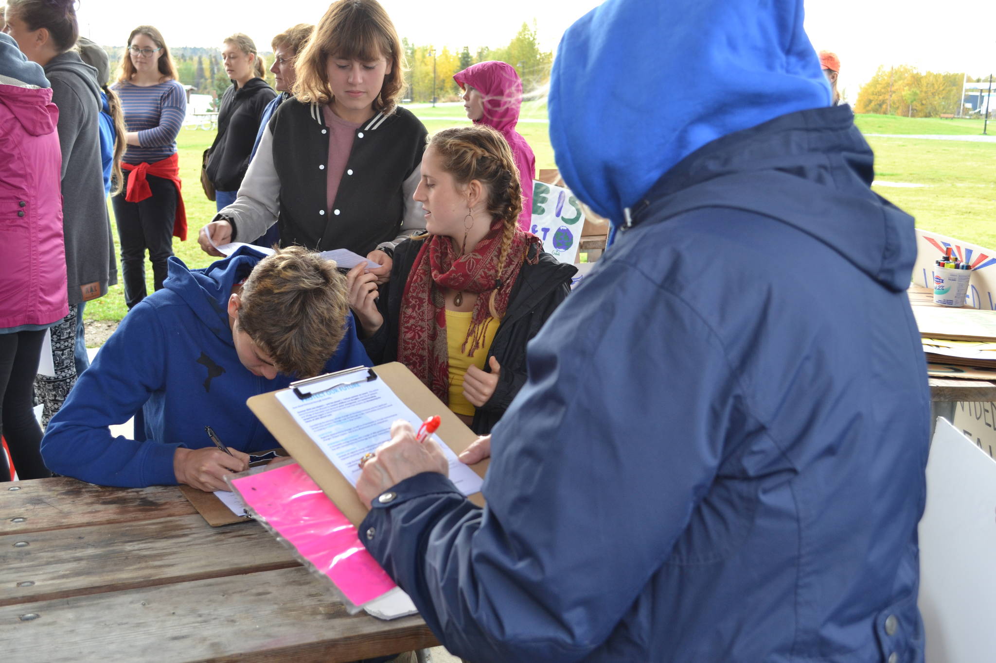 Climate Strike participants sign a petition asking the Kenai Peninsula Borough to incorporate climate change into the borough’s comprehensive plan during Soldotna’s Climate Strike on Sept. 20, 2019. (Photo by Brian Mazurek/Peninsula Clarion)