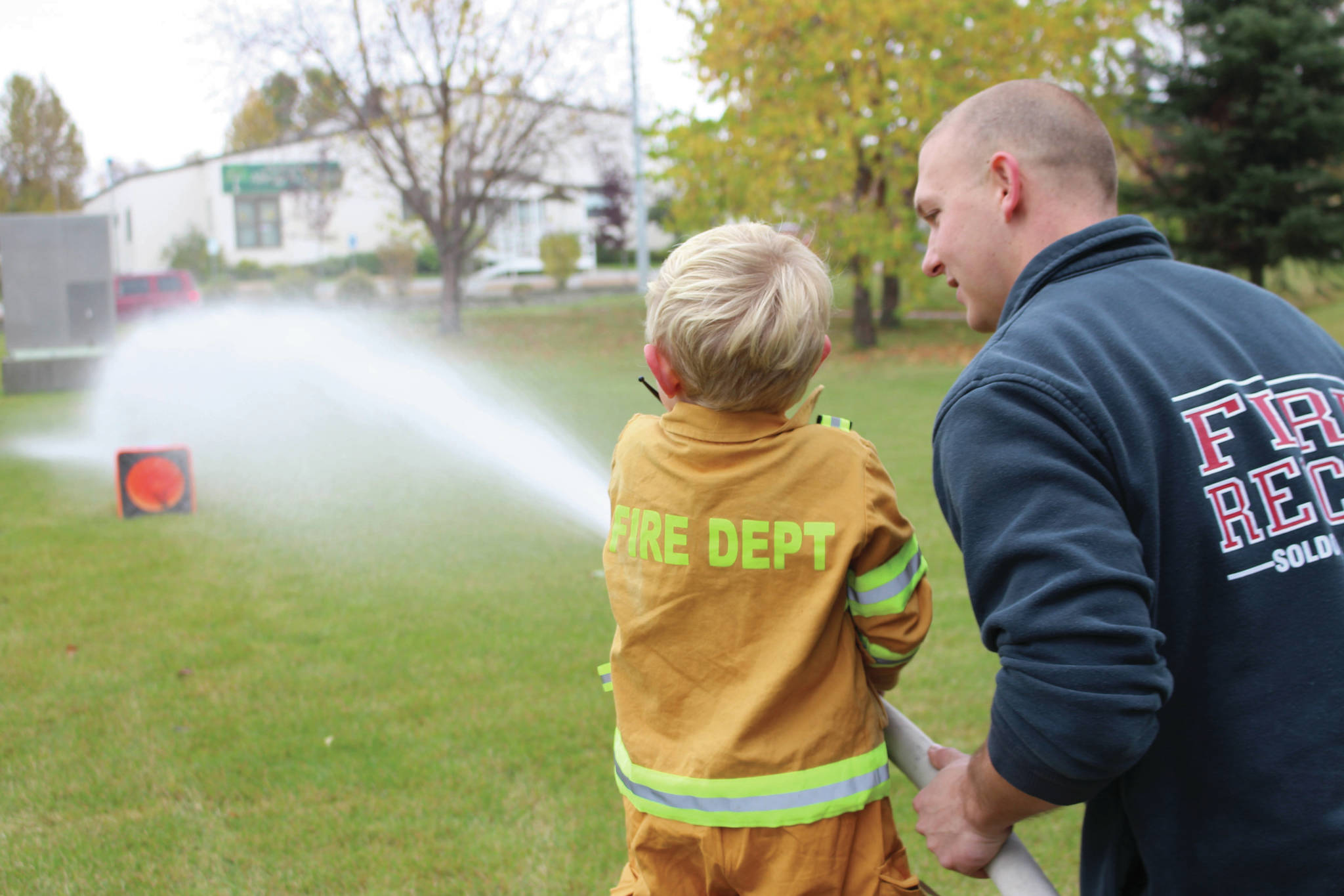Brian Mazurek / Peninsula Clarion                                A young firefighter-in-training practices knocking down a water jug with a fire hose during the Central Emergency Services Open House at Fire Station 1 in Soldotna, Saturday.