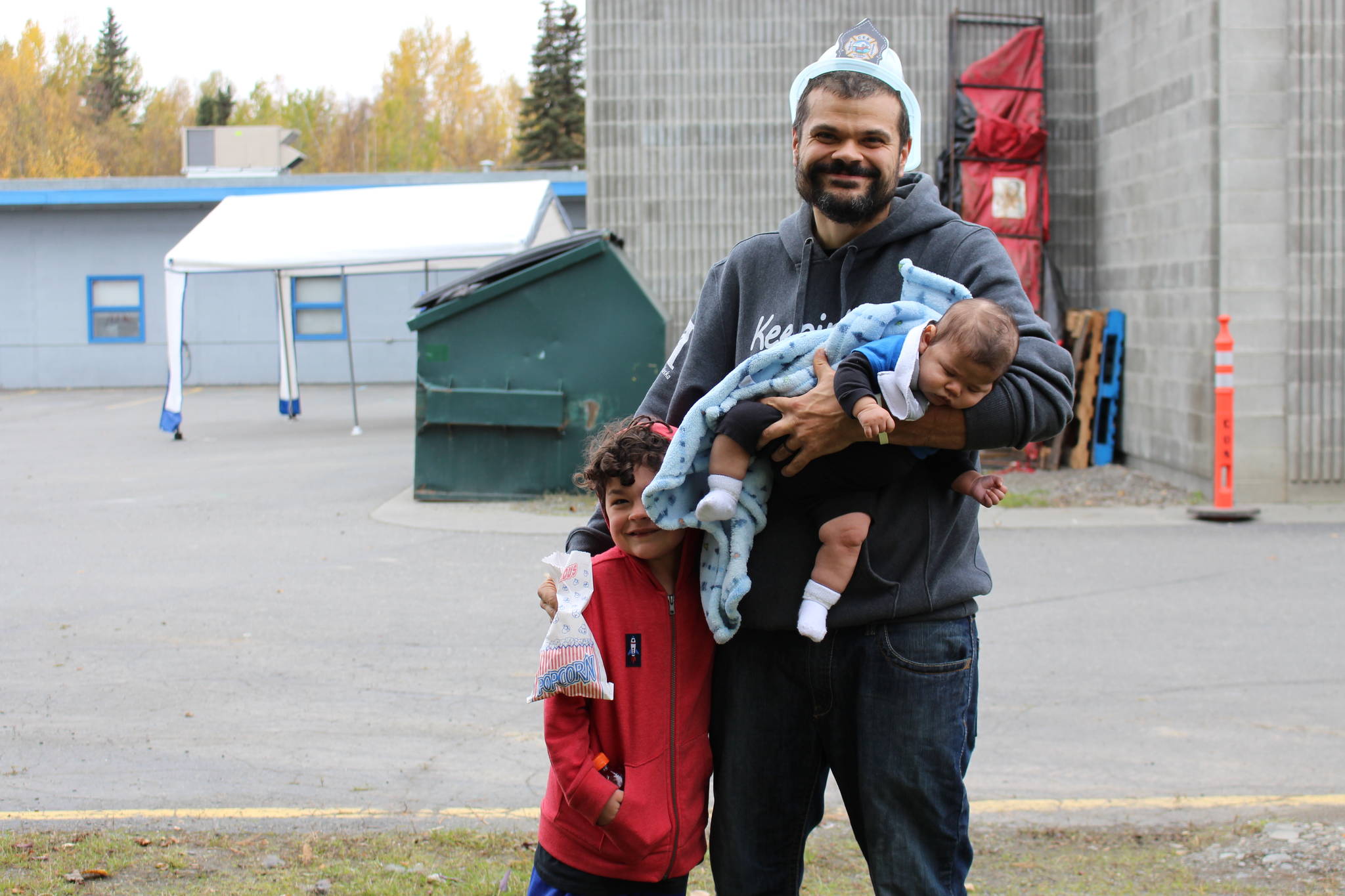 From left, Manny Peterson, Jacob Peterson and baby Ezra Peterson smile for the camera during the Central Emergency Services Open House at Fire Station 1 in Soldotna, Alaska on Sept. 28, 2019. (Photo by Brian Mazurek/Peninsula Clarion)