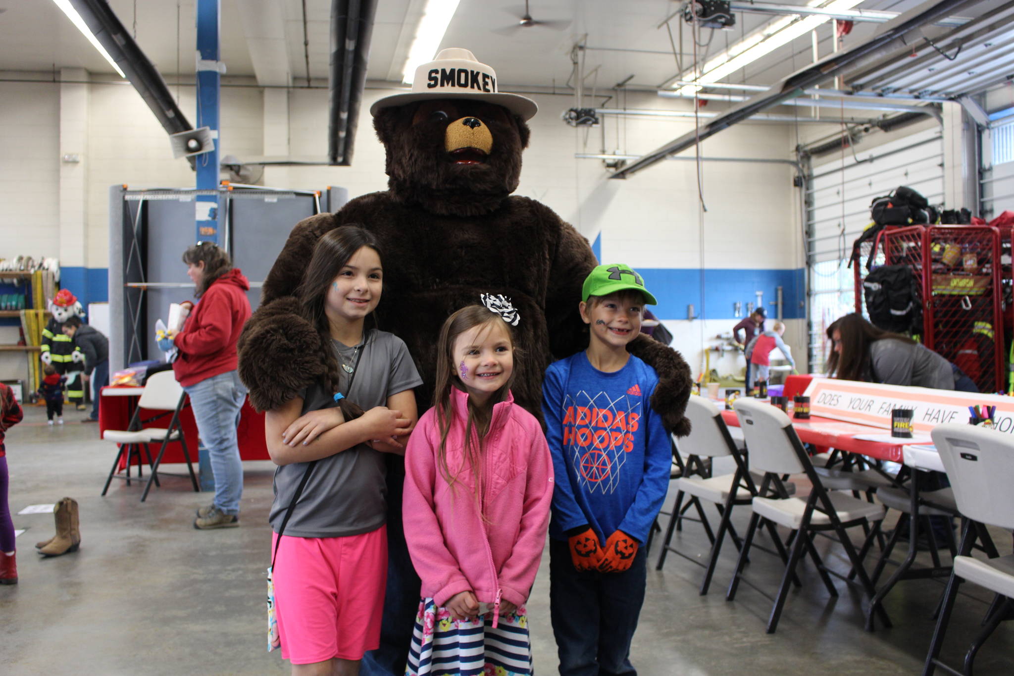 Lily Ratliff, Addy Ratliff and Jaxon Ratliff pose with Smokey the Bear during the Central Emergency Services Open House at Fire Station 1 in Soldotna, Alaska on Sept. 28, 2019. (Photo by Brian Mazurek/Peninsula Clarion)
