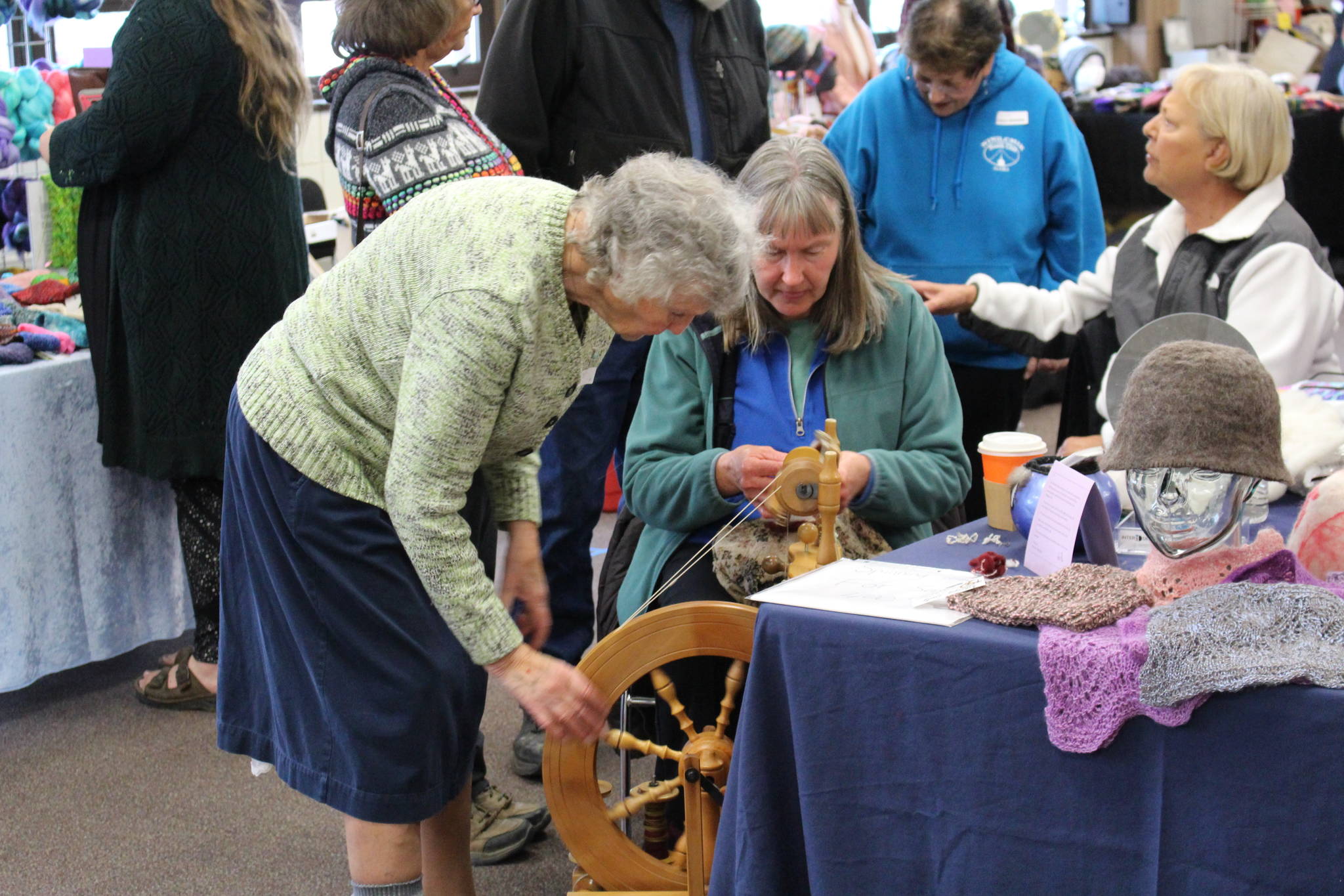 Alrene Haines, left instructs Donna Jones, right on how to use a spinning wheel during the Fireweed FiberFest at the Soldotna Regional Sports Complex on Sept. 28, 2019. (Photo by Brian Mazurek/Peninsula Clarion)