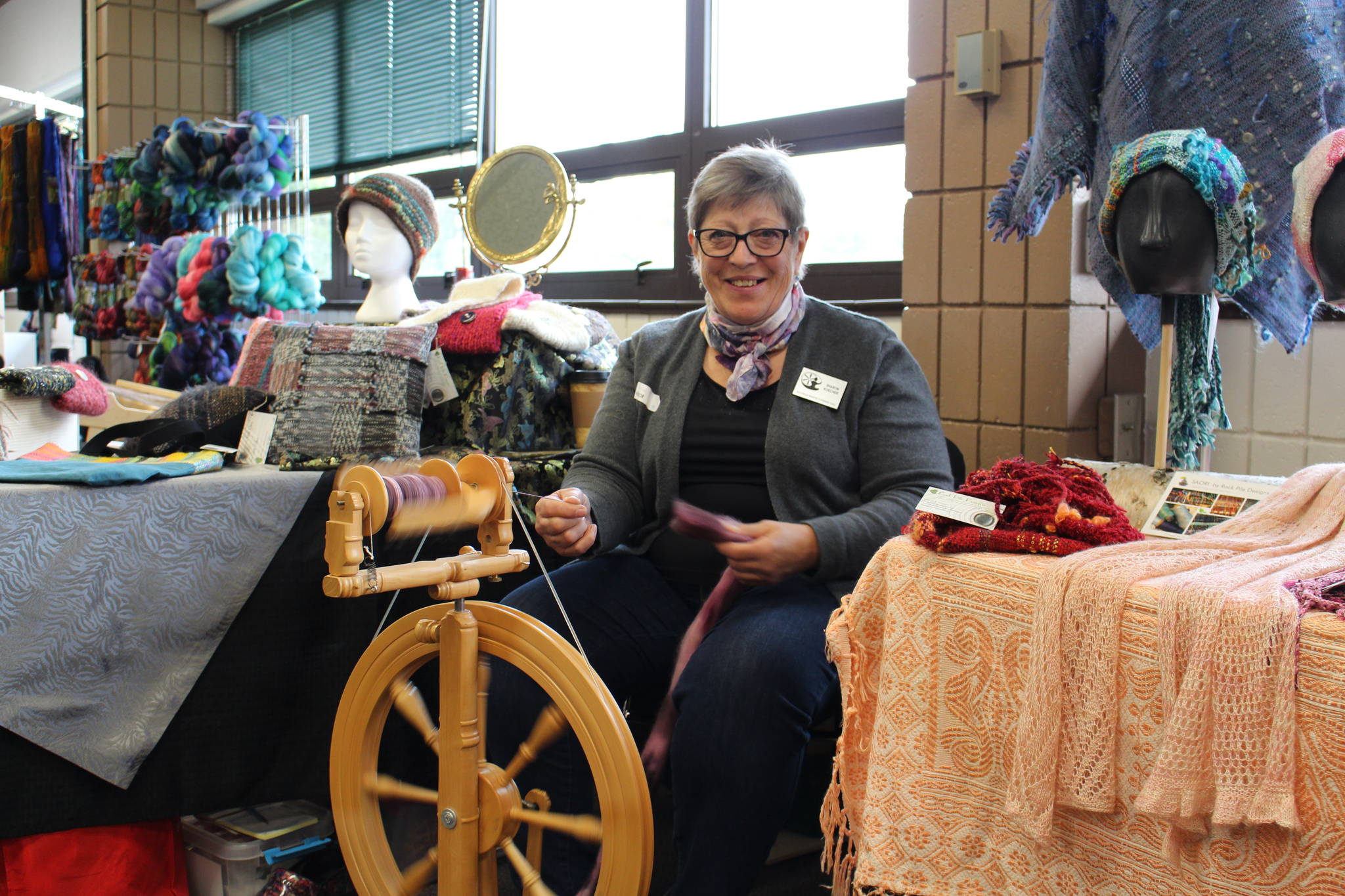 Sharon Koecher sits at her spinning wheel and shows off her wares during the Fireweed FiberFest at the Soldotna Regional Sports Complex in Soldotna, Alaska on Sept. 28, 2019. (Photo by Brian Mazurek/Peninsula Clarion)