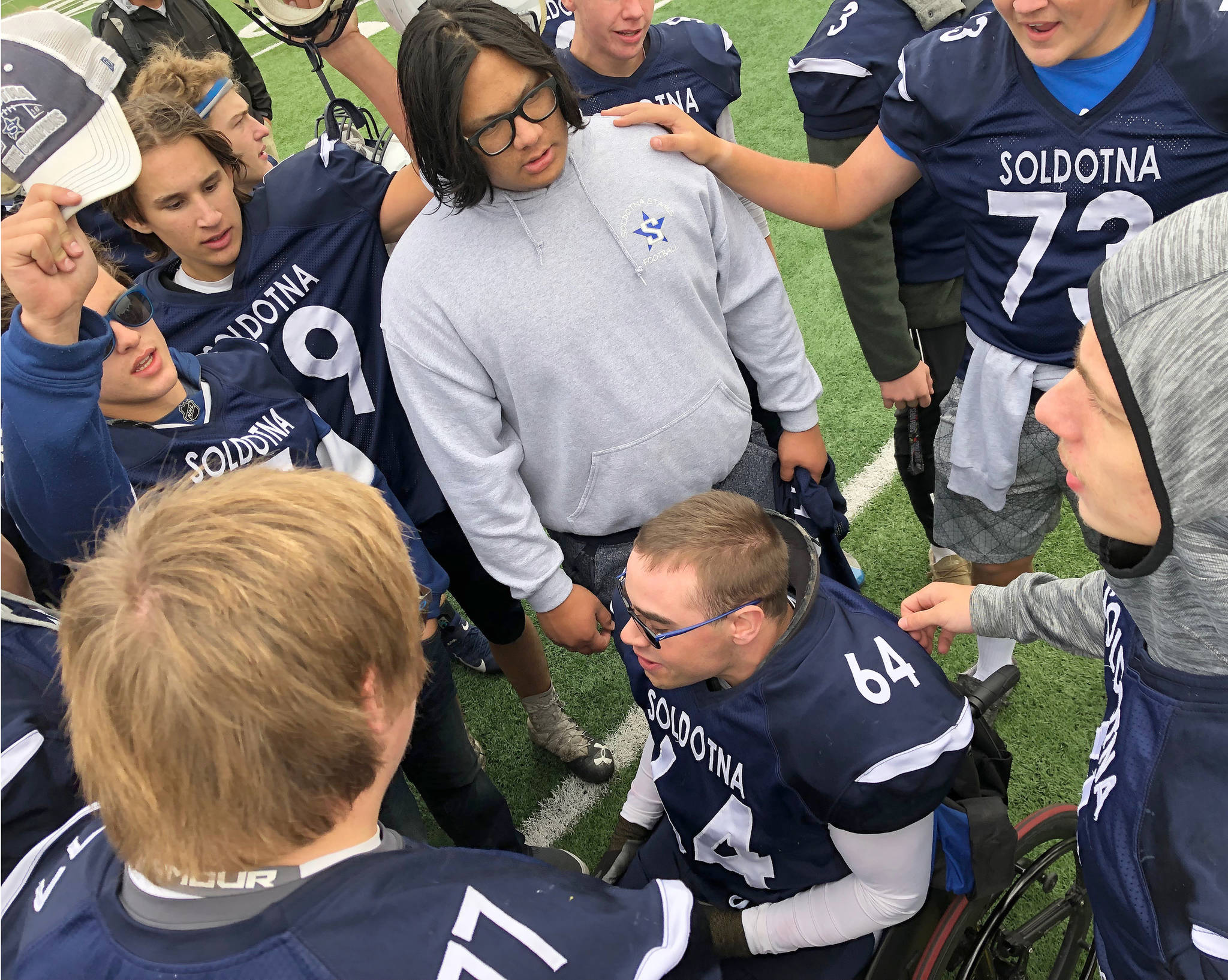 The Soldotna varsity football team crowds around senior manager Matthew Martinelli Saturday after defeating Eagle River 81-7 at Justin Maile Field in Soldotna. (Photo by Joey Klecka/Peninsula Clarion)