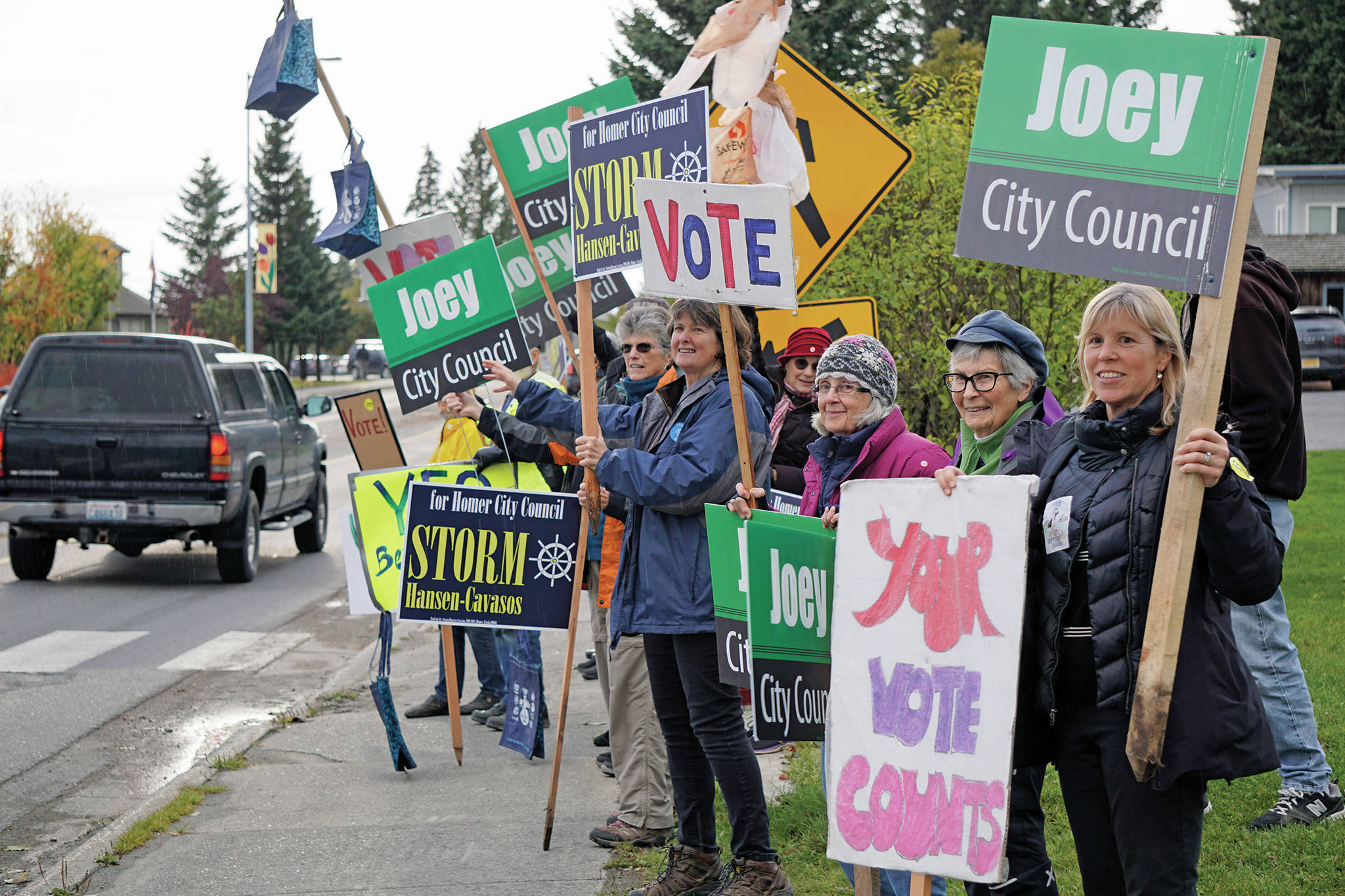 Supporters wave signs in support of Proposition A, to ban single-use plastic bags, and for Homer City Council candidates Joey Evensen and Storm Hansen-Cavasos on Tuesday, Oct. 1, 2019, at WKFL Park in Homer, Alaska. (Photo by Michael Armstrong/Homer News)