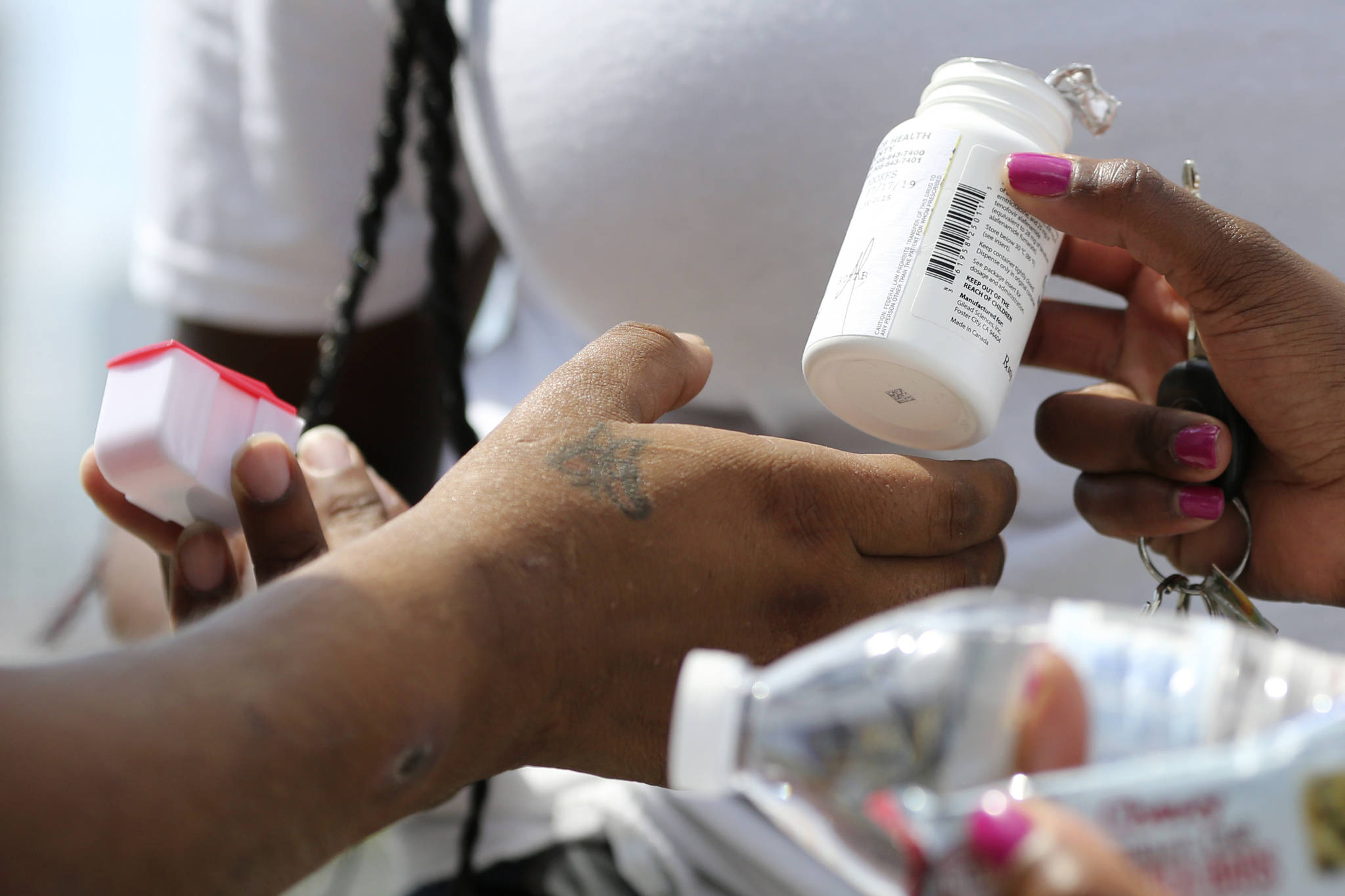 In this July photo Ivette Naida, left, receives HIV medication from social workers from the IDEA Exchange. HIV medication is part of the reason transmission rates of the virus are low in Alaska. (AP Photo | Lynne Sladky)