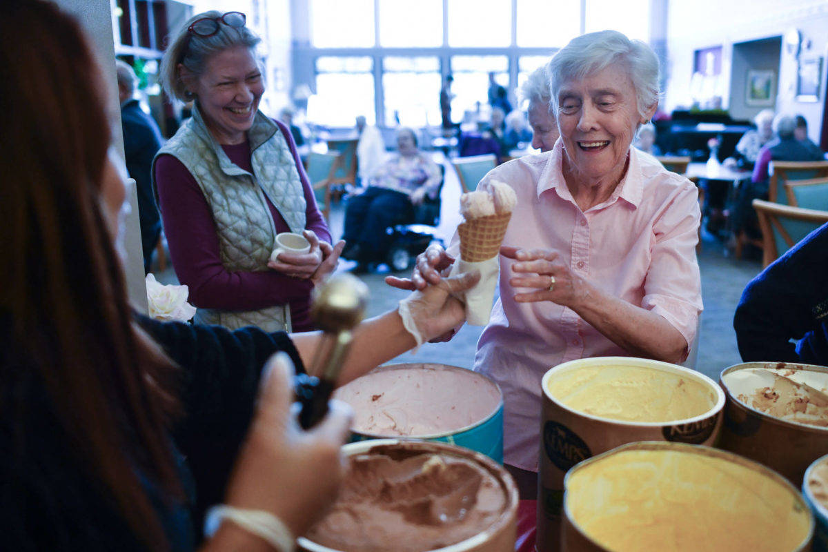 Alaska Pioneer Home resident Phyllis Woodman, right, receives a cone of ice cream from employee Myra Kalbaugh during the home’s weekly ice cream social on Friday, March 8, 2019. (Michael Penn | Juneau Empire)