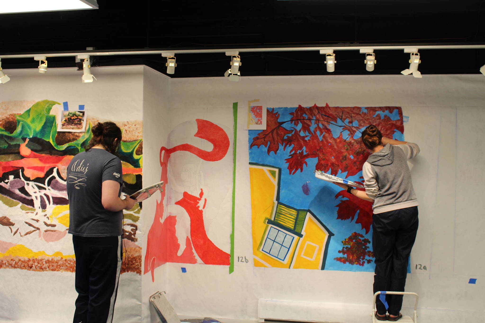 Artists Jason Ramirez, left, and Tasha Skolnick, right, work on their portion of the “Gather” mural at the Kenai Fine Art Center in Kenai, Alaska, on Saturday, Nov. 2, 2019. (Photo by Brian Mazurek/Peninsula Clarion)