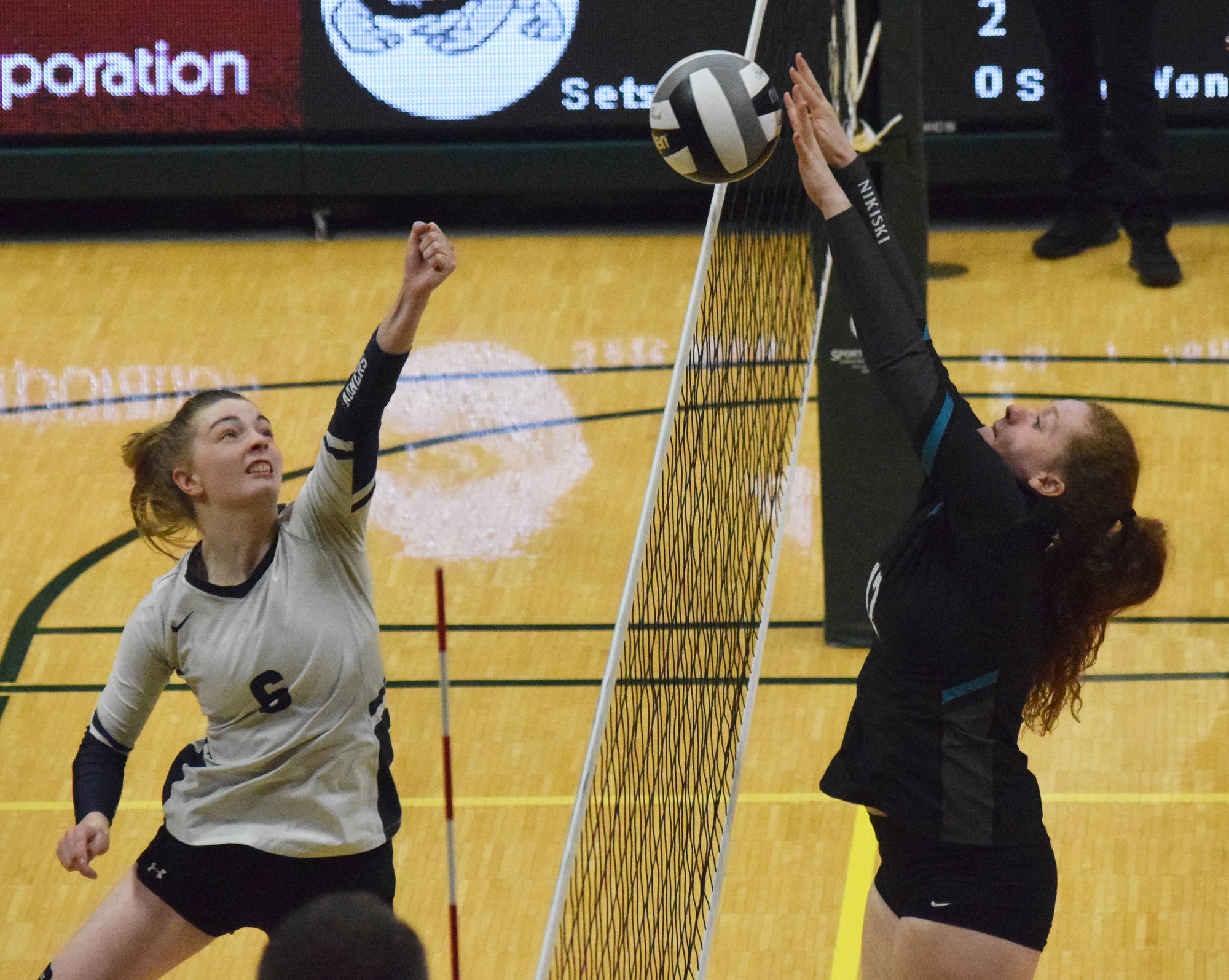Homer’s Karmyn Gallios (left) punches the ball against Nikiski’s Kaycee Bostic, Thursday, Nov. 14, 2019, at the Class 3A state volleyball tournament at the Alaska Airlines Center in Anchorage, Alaska. (Photo by Joey Klecka/Peninsula Clarion)