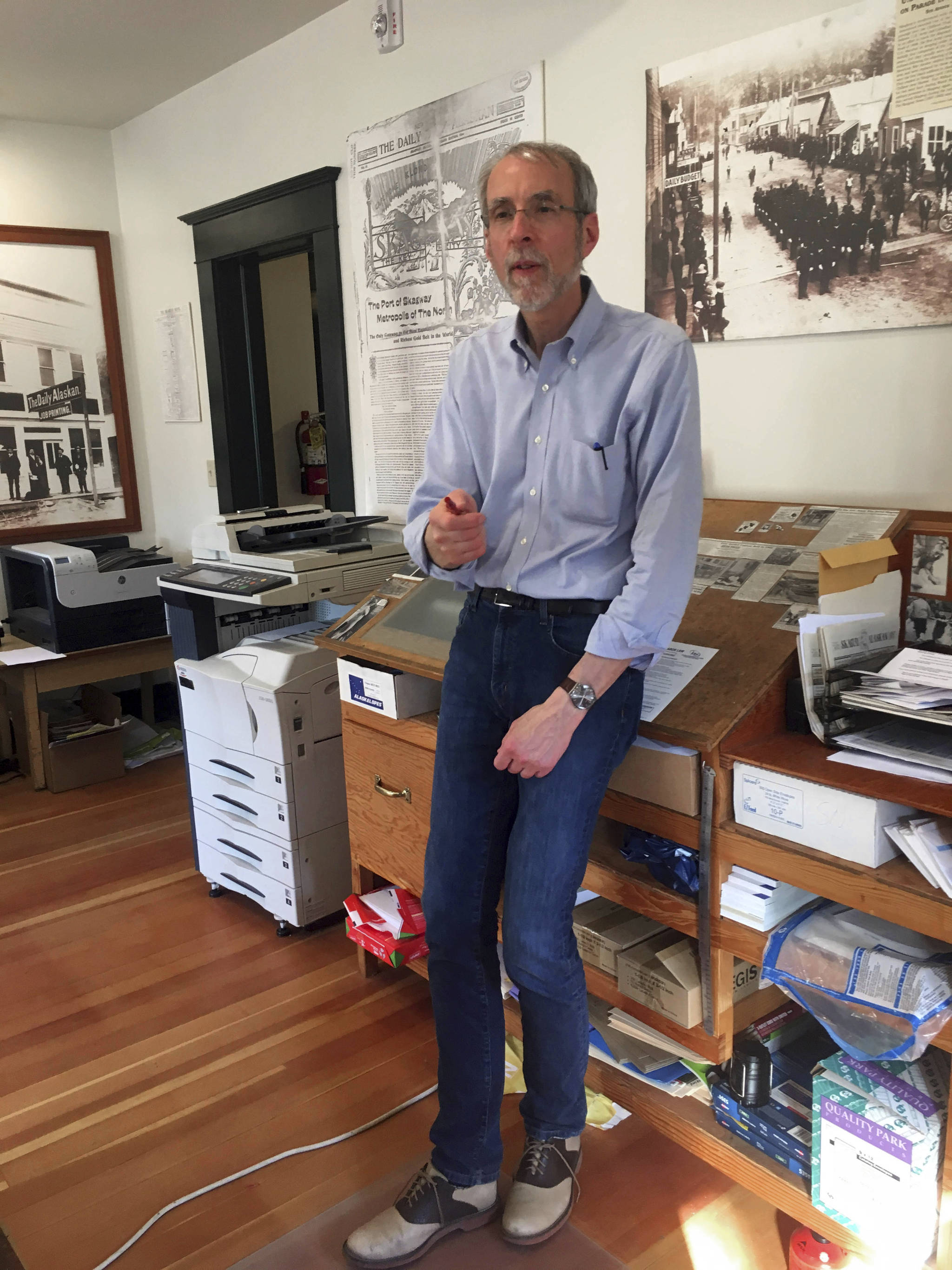 This May 29, 2019 photo shows Larry Persily, the publisher of The Skagway News, in the newspaper office in Skagway, Alaska. If you’ve ever wanted to own a small bi-weekly newspaper in Alaska but didn’t have the money, this could be your chance. The publisher of The Skagway News is willing to give the paper away to the right person, if they are willing to move to the southeast Alaska community and be a part of the community. Persily says he’s willing to help out the new owners by giving away the paper because the advertising will afford them a living wage, but not on top of a mortgage. (Molly McCammon via AP)