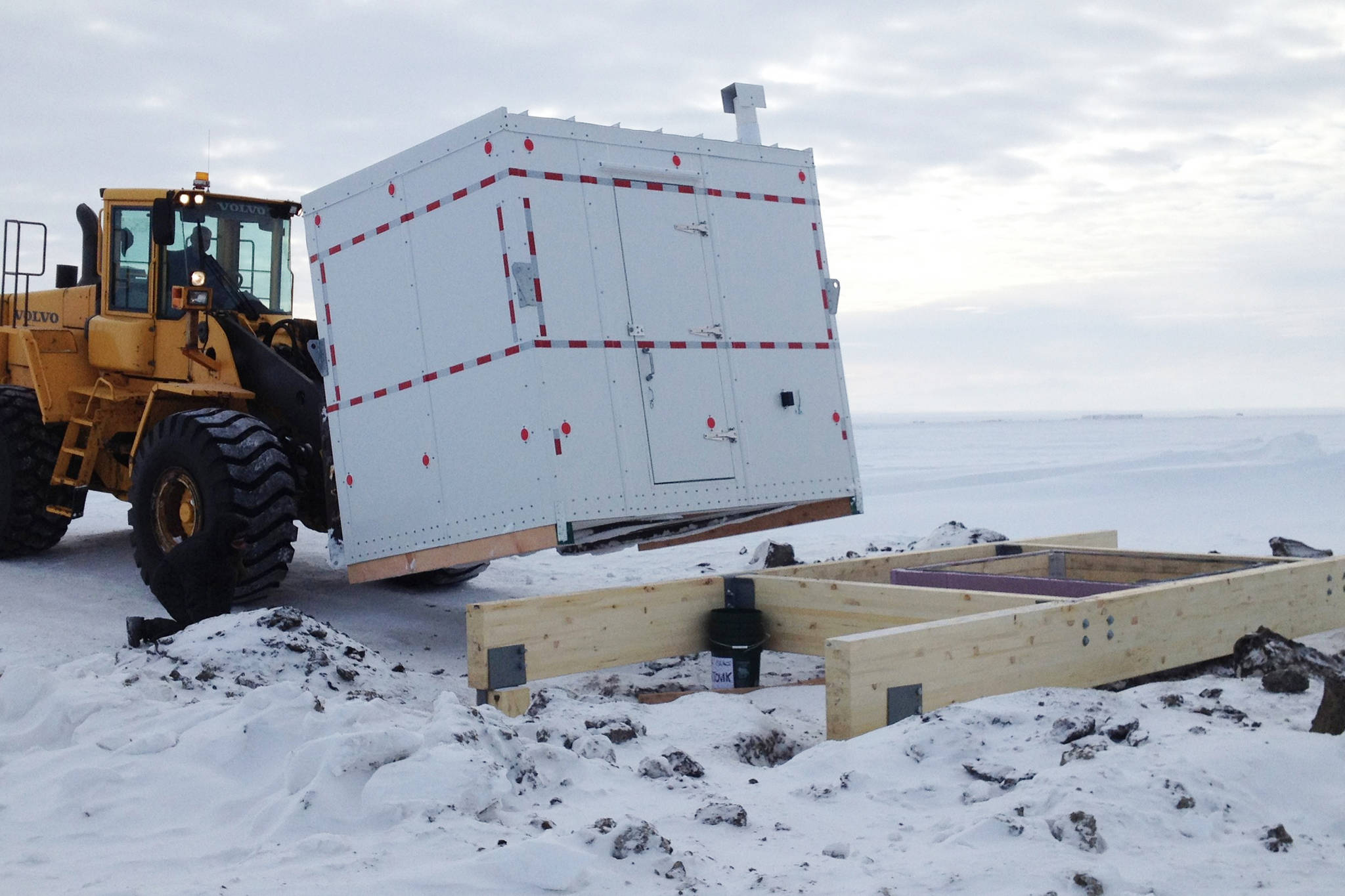 This undated photo in Kaktovik, Alaska, shows installation of a shelter covering the entrance to a new community ice cellar, a type of underground food cache dug into the permafrost to provide natural refrigeration used for generations in far-north communities. Naturally cooled underground ice cellars, used in Alaska Native communities for generations, are becoming increasingly unreliable as a warming climate and other factors touch multiple facets of life in the far north. (Marnie Isaacs/Kaktovik Community Foundation via AP)