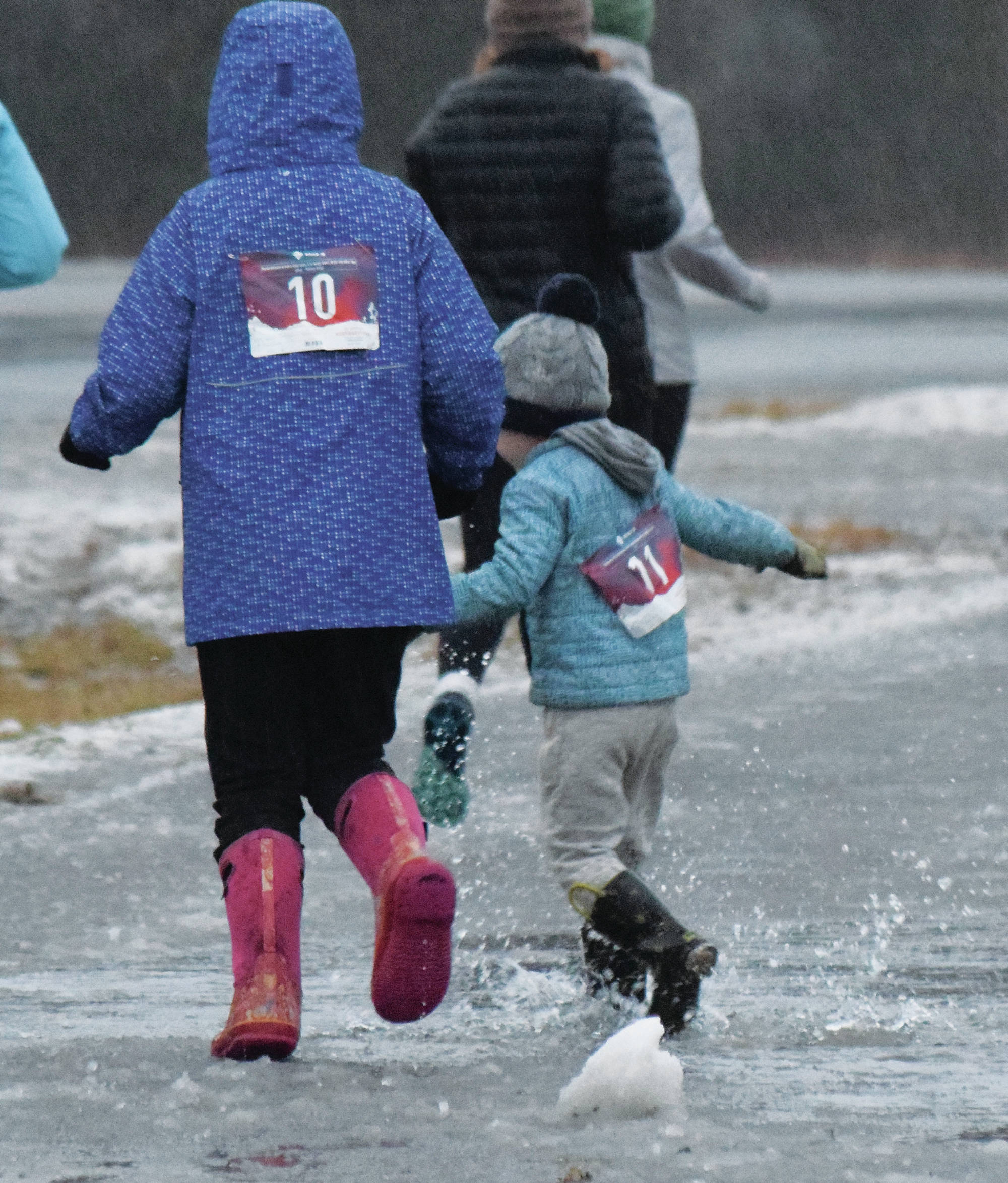 A youth runner splashes through a puddle early on Thursday, Nov. 28, 2019, at the Turkey Trot in Soldotna, Alaska. (Photo by Joey Klecka/Peninsula Clarion)