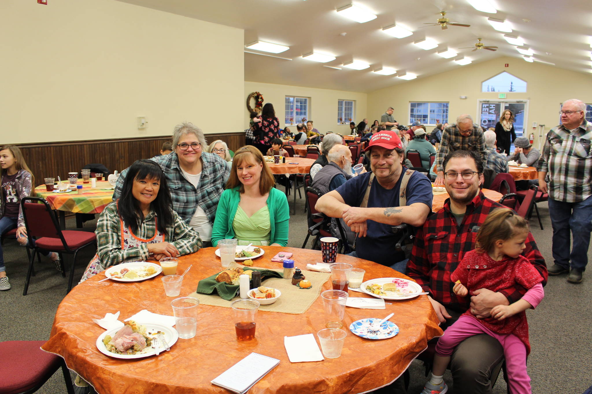 From left, Priscilla Tapangco, Carol Kvasnikoff, Annaleah Karron, Mike Karron, Charlie Karron and Allison Karron smile for the camera during the Thanksgiving community potluck at College Heights Baptist Church in Soldotna, Alaska, on Thursday, Nov. 28, 2019. (Photo by Brian Mazurek/Peninsula Clarion)