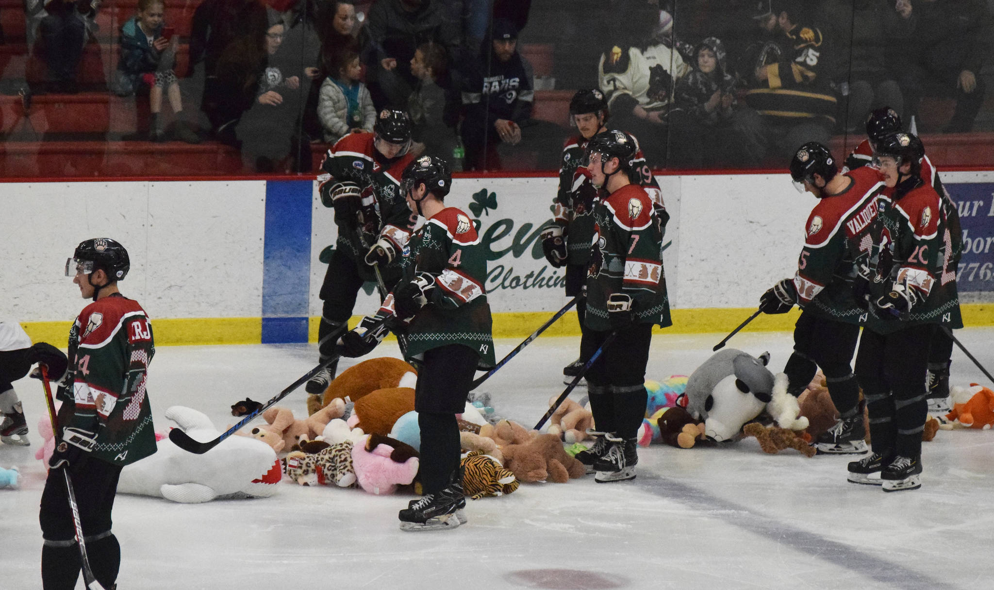 Kenai River players help clean up dozens of toy animals that were thrown onto the ice following the first goal between the Kenai River Brown Bears and Minnesota Magicians, Friday, Nov. 29, 2019, at the Soldotna Regional Sports Complex in Soldotna, Alaska. The stuffed animal toss was part of a charity event for the Salvation Army. (Photo by Joey Klecka/Peninsula Clarion)