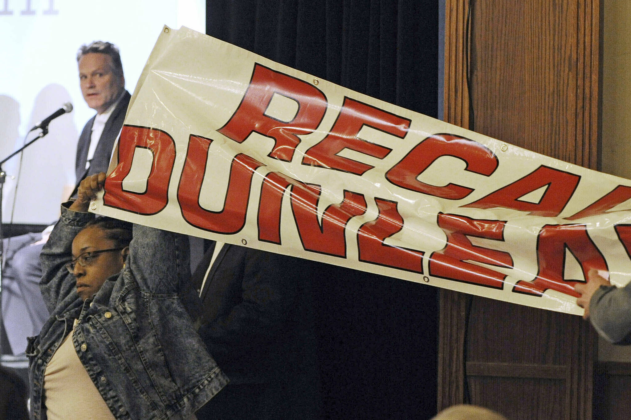In this March 26, 2019, file photo, protestors unfurl a “Recall Dunleavy” banner as Gov. Mike Dunleavy, upper left, speaks during a roadshow with Americans for Prosperity in 49th State Brewing Company in Anchorage, Alaska. Dunleavy said he hopes to move past the rancor of his first year in office, amid an unsettled dispute with lawmakers over state spending and threat of a recall effort looming large. The Republican will mark a full year in office Tuesday, Dec. 3. (Bill Roth/Anchorage Daily News via AP, File)