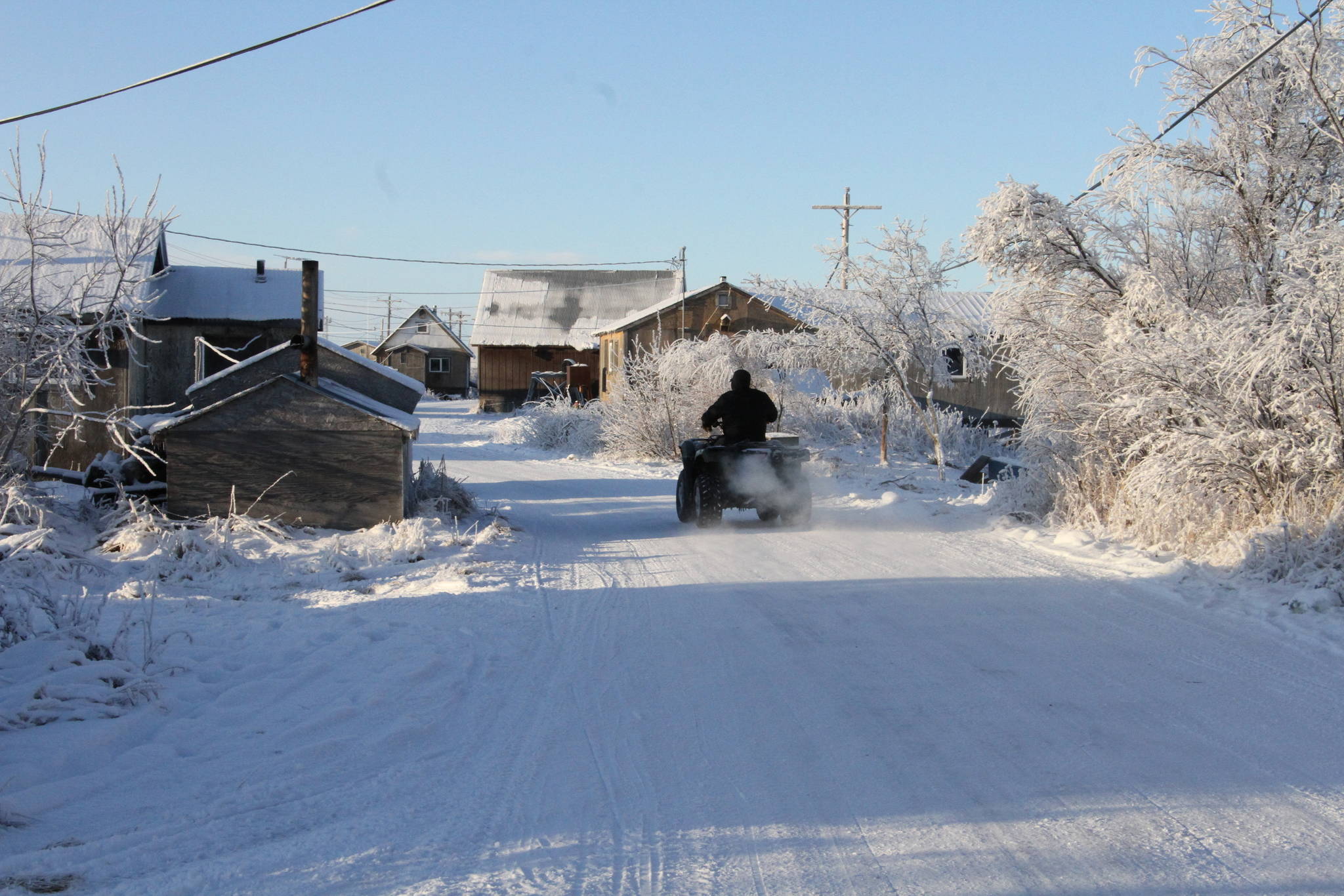 This Dec. 3, 2019, photo shows a man driving a four-wheeler down a street in Napakiak, Alaska. The Alaska National Guard brought its Operation Santa Claus to the western Alaska community, which is being severely eroded by the nearby Kuskokwim River. (AP Photo/Mark Thiessen)