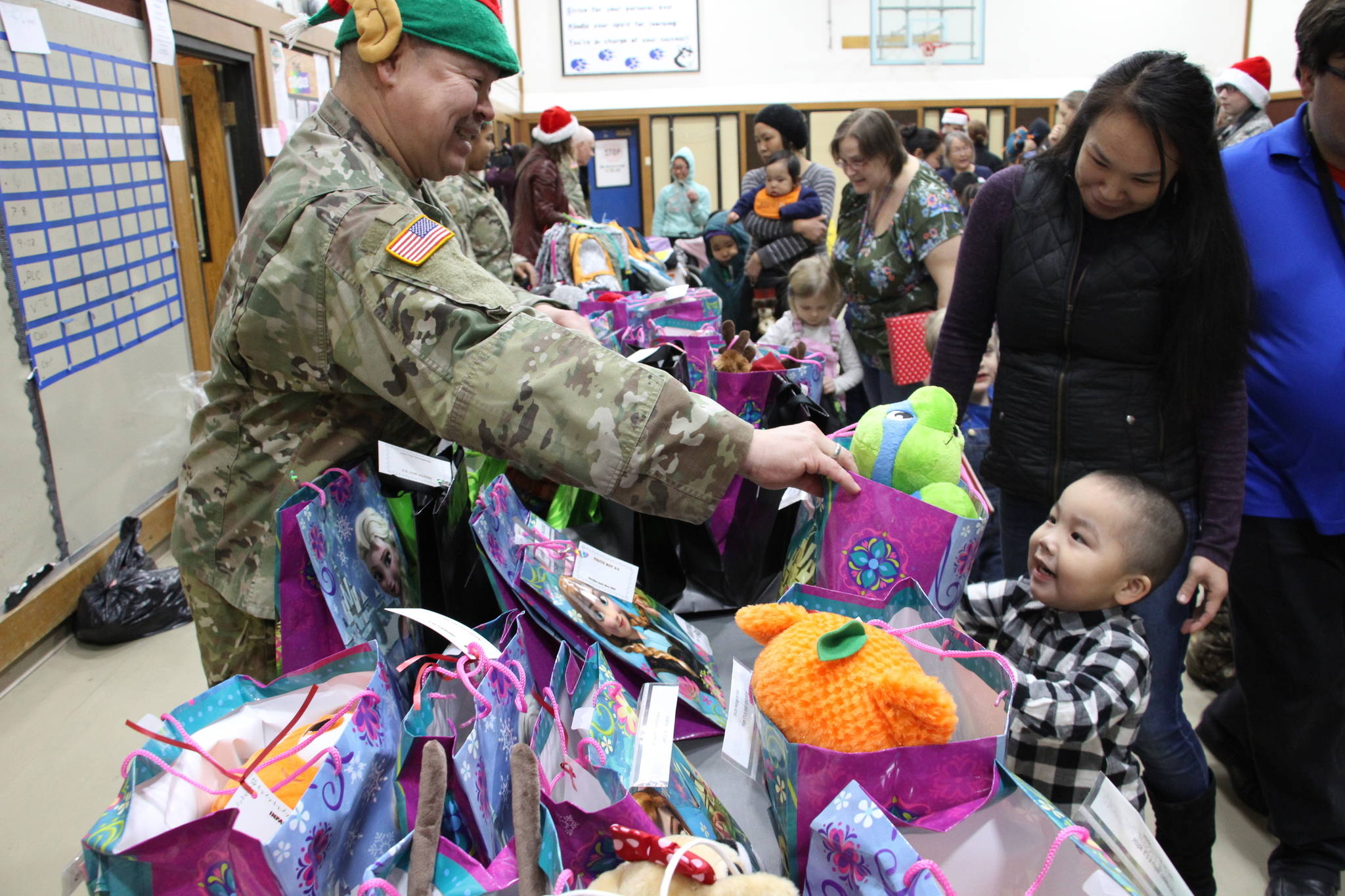 This Dec. 3, 2019, photo shows Alaska National Guard Staff Sgt. Joseph Sallaffie handing a gift bag to Corban Jimmy while Marlene Black looks on during Santa’s visit to Napakiak, Alaska. The Alaska National Guard brought its Operation Santa Claus to the western Alaska community, which is being severely eroded by the nearby Kuskokwim River. (AP Photo/Mark Thiessen)
