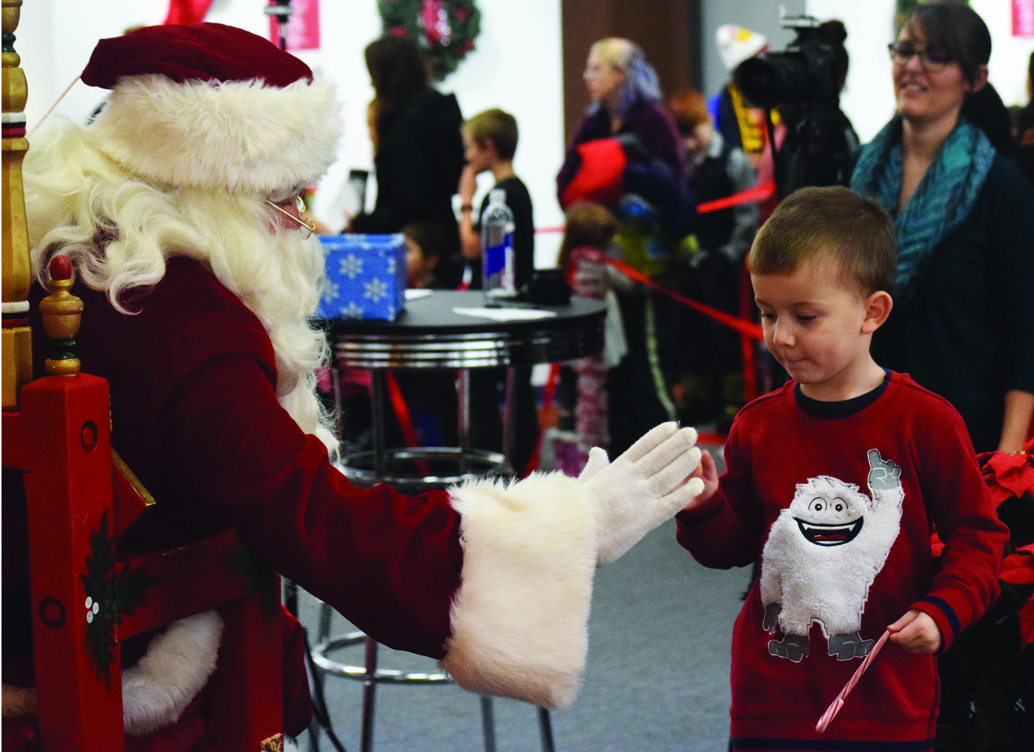 Santa Claus gives a young fan a high five Friday, Nov. 29 at the Christmas Comes to Kenai celebration at the Kenai Visitor and Cultural Center. (Photo by Joey Klecka/Peninsula Clarion)