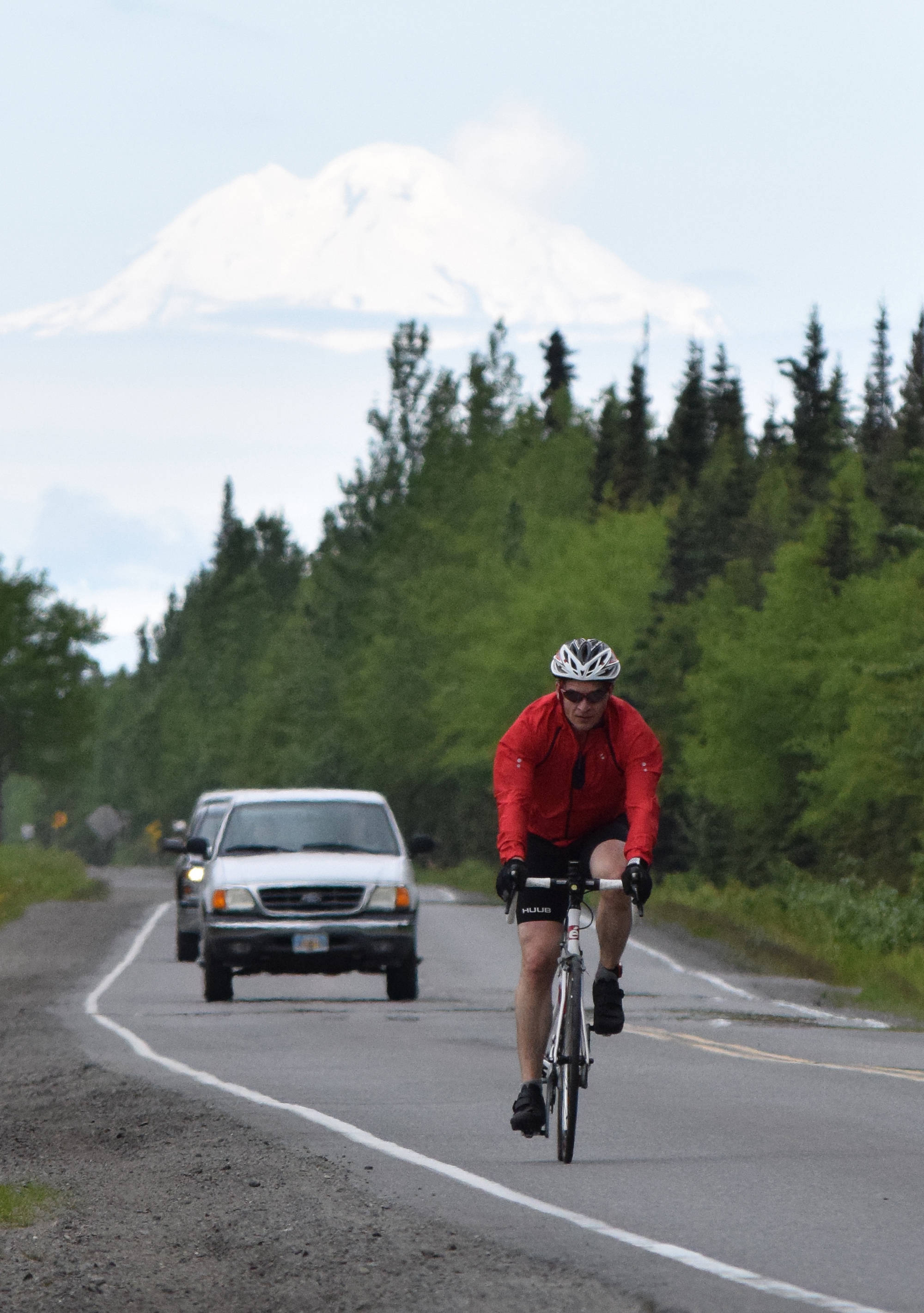 Anchorage’s John Krellner rides down Gas Well Road with Mount Redoubt in the background Sunday, June 9, 2019, in the Tri-The-Kenai Triathlon in Soldotna, Alaska. (Photo by Joey Klecka/Peninsula Clarion)