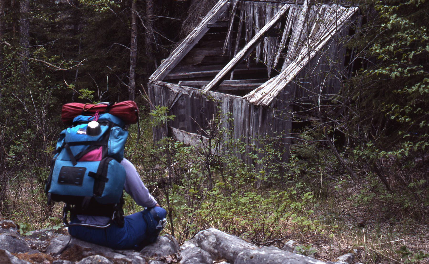 A hiker rests near the remains of an old Surprise Creek mine structure, June 1990. (Photo by Clark Fair)