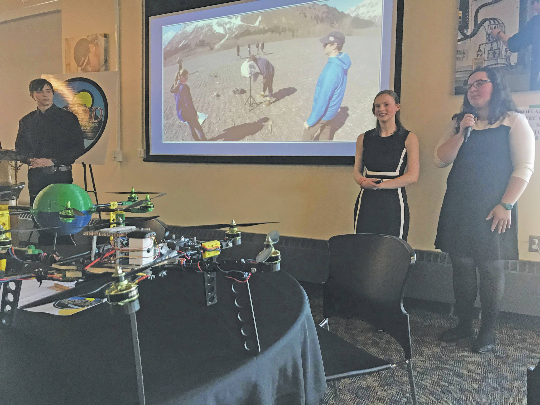 Seward High School students (from left) Tayten Barhaug, Lindy Guernsey and Akilena Veach demonstrate their Caring for the Kenai project, drones to help map the flood planes of Seward, during the Industry Outlook Forum in Seward on Wednesday, Jan. 8, 2019. (Photo by Kat Sorensen/Peninsula Clarion)