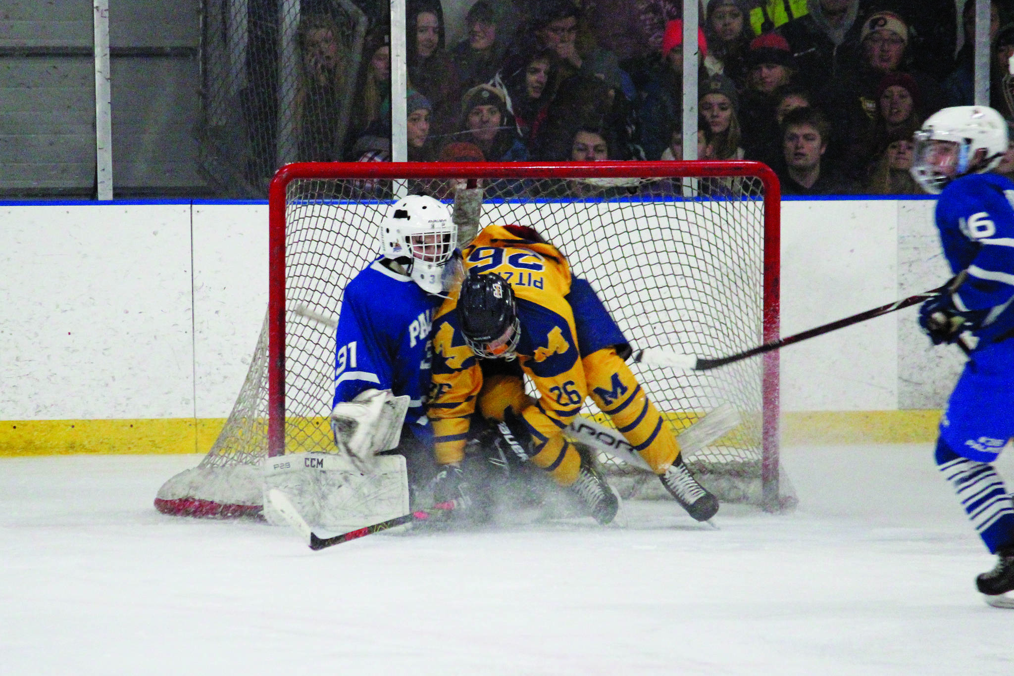 Homer’s Ethan Pitzman crashes into the net and into Palmer goaltender Tiernan O’Rourke after an unsuccessful shot on goal Thursday, Jan. 9, 2020 during a hockey game at Kevin Bell Arena in Homer, Alaska. (Photo by Megan Pacer/Homer News)