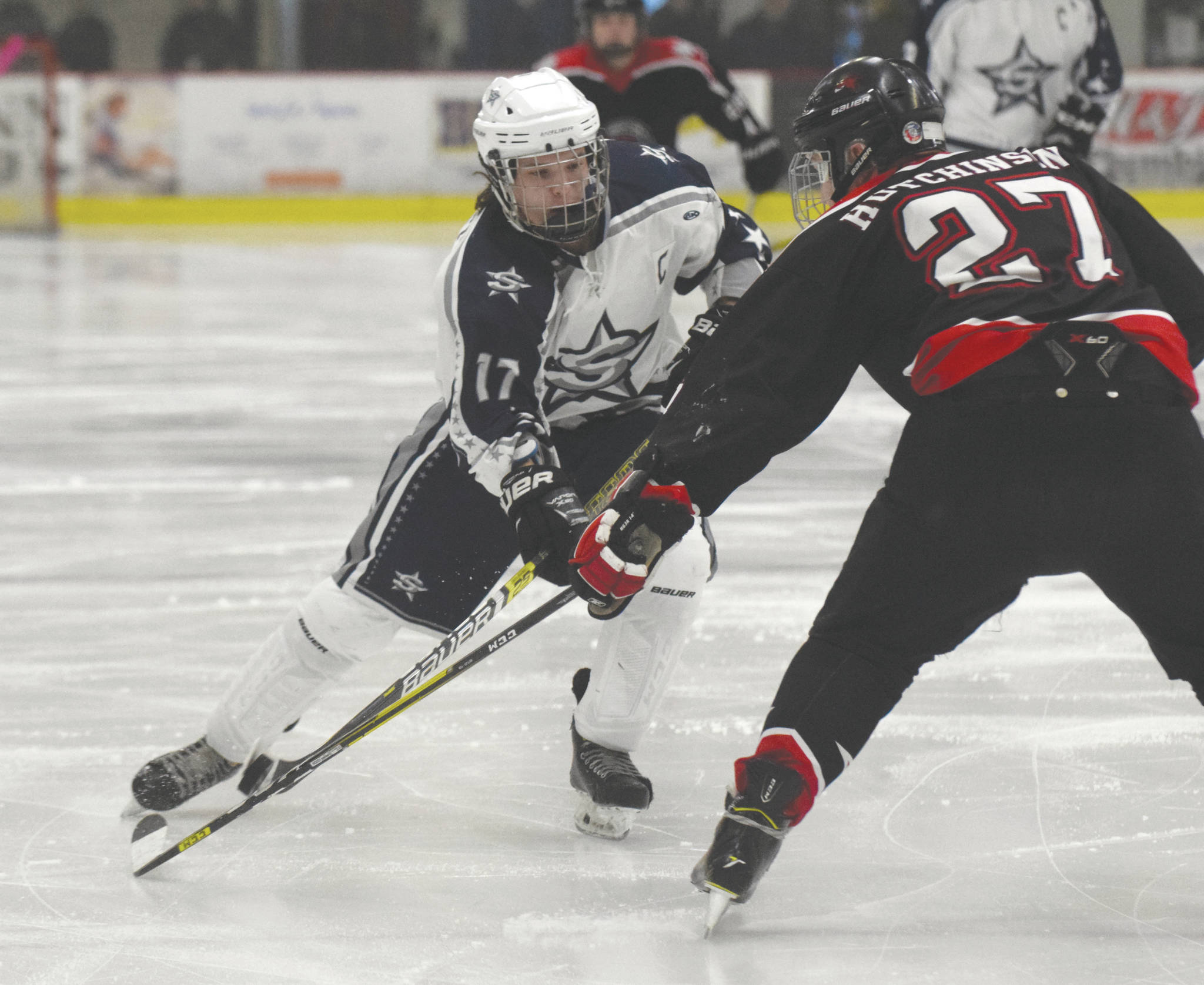 Soldotna’s Wyatt Medcoff chips the puck past Houston’s Nate Hutchinson on Friday, Jan. 10, 2019, at the Soldotna Regional Sports Complex in Soldotna, Alaska. (Photo by Jeff Helminiak/Peninsula Clarion)
