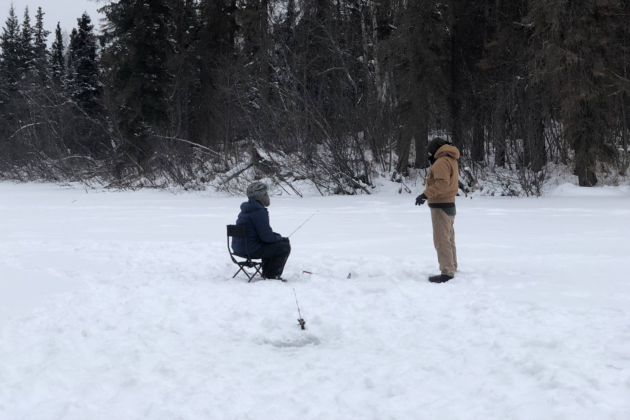 Brian Mazurek, left, and Ben Weagraff, right, are seen ice fishing on Paddle Lake off of Swan Lake Road in Sterling, Alaska on Feb. 2, 2020. (Photo by Victoria Petersen/Peninsula Clarion)