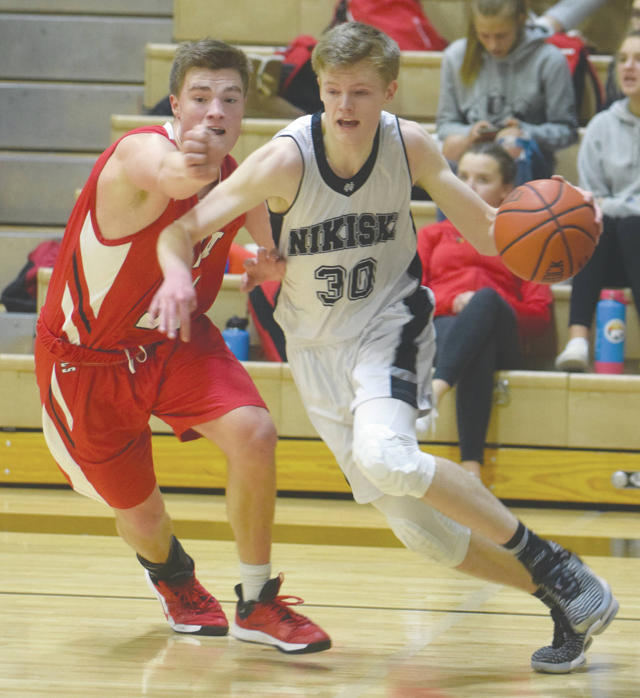 Nikiski’s Austin Stafford drives on Kenai Central’s Braedon Pitsch on Tuesday, Feb. 25, 2020, at Nikiski High School in Nikiski, Alaska. (Photo by Jeff Helminiak/Peninsula Clarion)