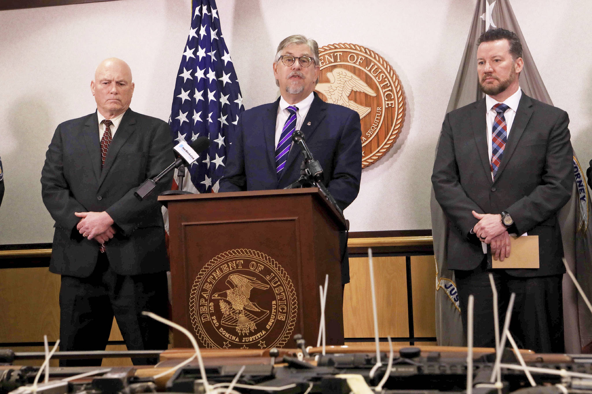 Bryan Schroder, center, U.S. attorney for Alaska, speaks at a press conference announcing the seizure of 82 illegally possessed guns in Anchorage and surrounding communities on Wednesday, Feb. 26, 2020, in Anchorage, Alaska. U.S Marshal Rob Heun, left, and Darek Pleasants of the Bureau of Alcohol, Tobacco and Firearms, right, look on. The investigation resulted in federal charges against 16 people for firearm or drug trafficking counts. (AP Photo/Dan Joling)