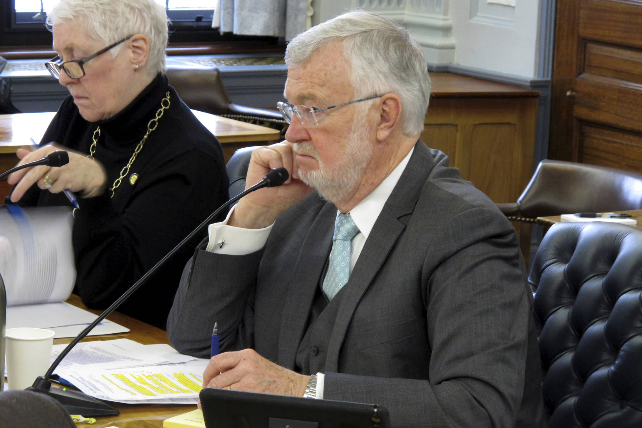 Alaska state Sen. Gary Stevens, right, listens during a Legislative Council meeting on Tuesday, March 10, 2020, in Juneau, Alaska. Stevens on Tuesday announced a subcommittee of lawmakers will work on contingency planning for the Legislature surrounding the new coronavirus. (AP Photo/Becky Bohrer)