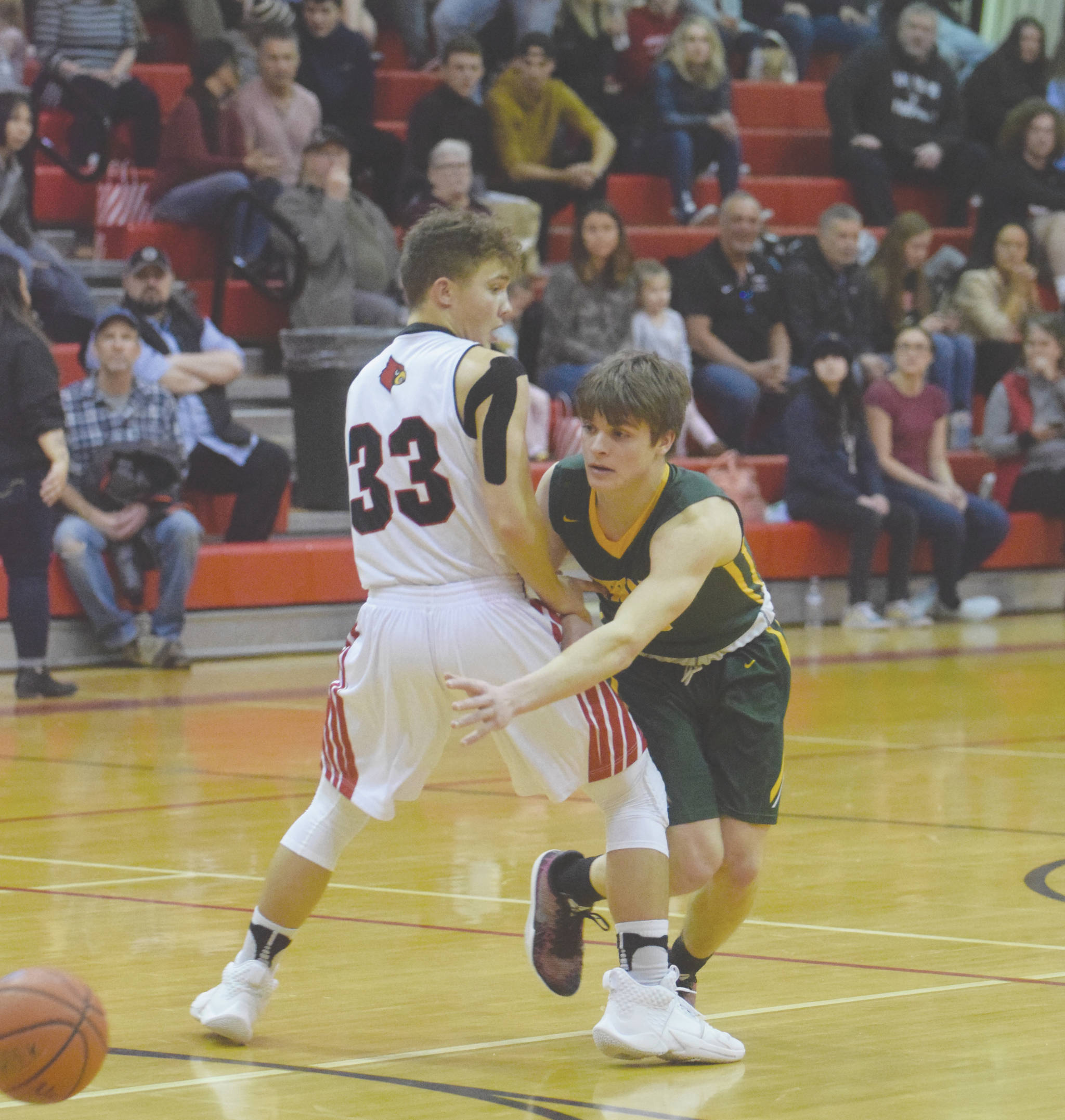 Seward’s Sam Koster passes around Kenai Central’s Kayden Daniels in front of a big crowd March 28, 2020, at Kenai Central High School in Kenai, Alaska. The state announced Friday there will be no after-school activiities until March 30, 2020, due to the new coronavirus. (Photo by Jeff Helminiak/Peninsula Clarion)